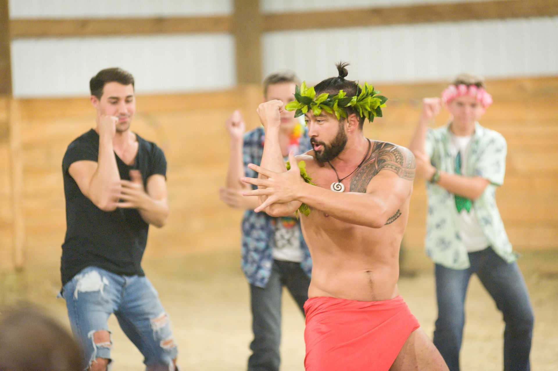 A group of men are dancing together in a barn.