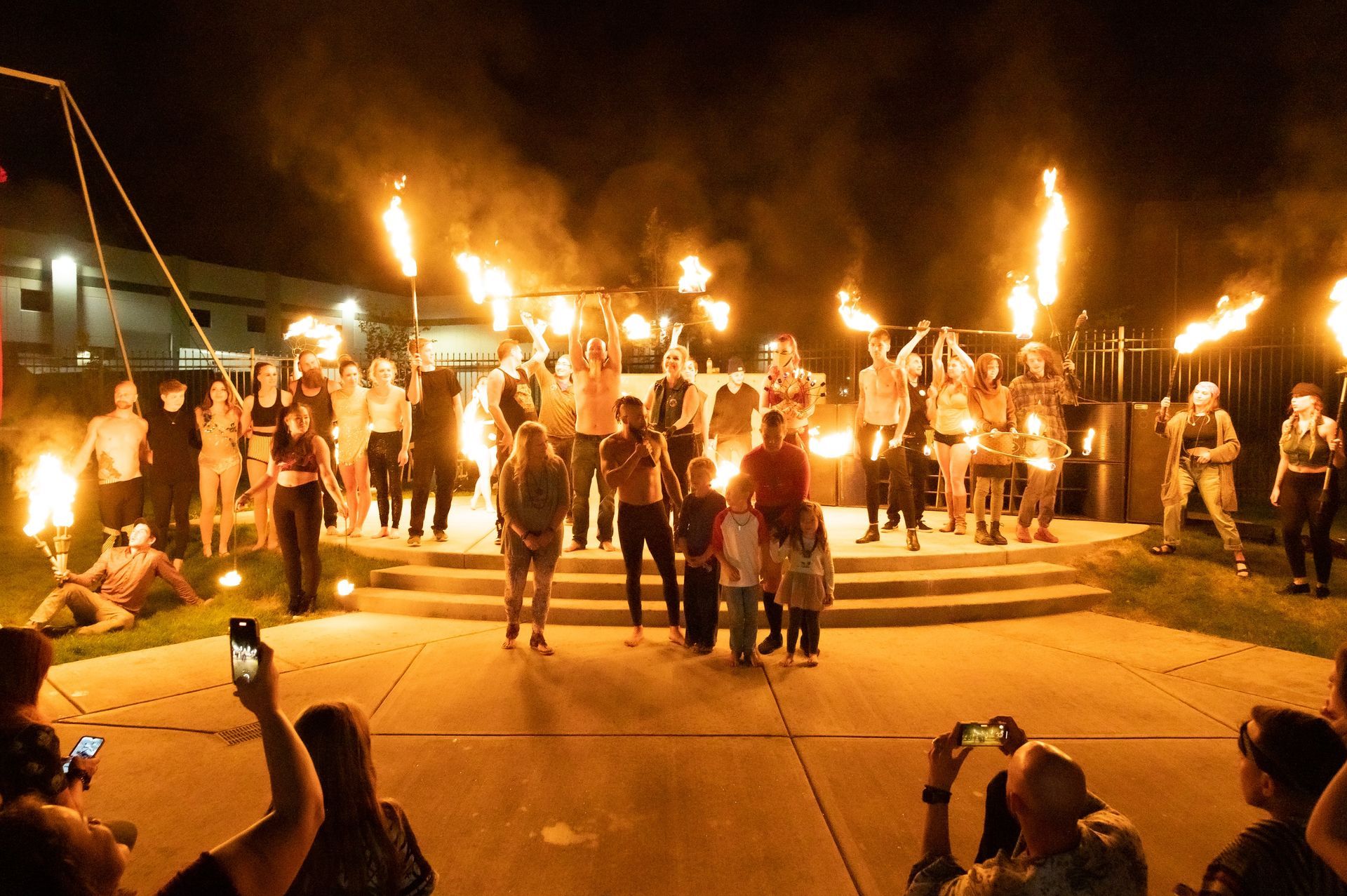 A group of people are standing in front of a fire at night.