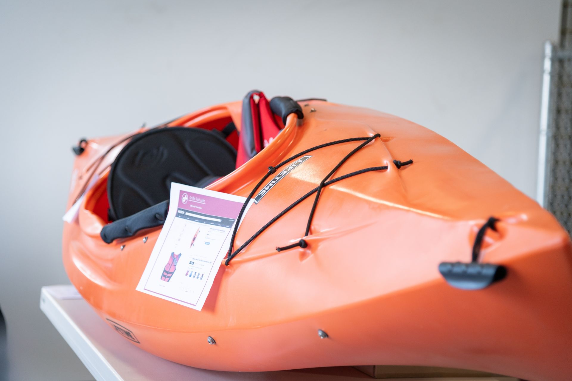 An orange kayak is sitting on top of a white table.