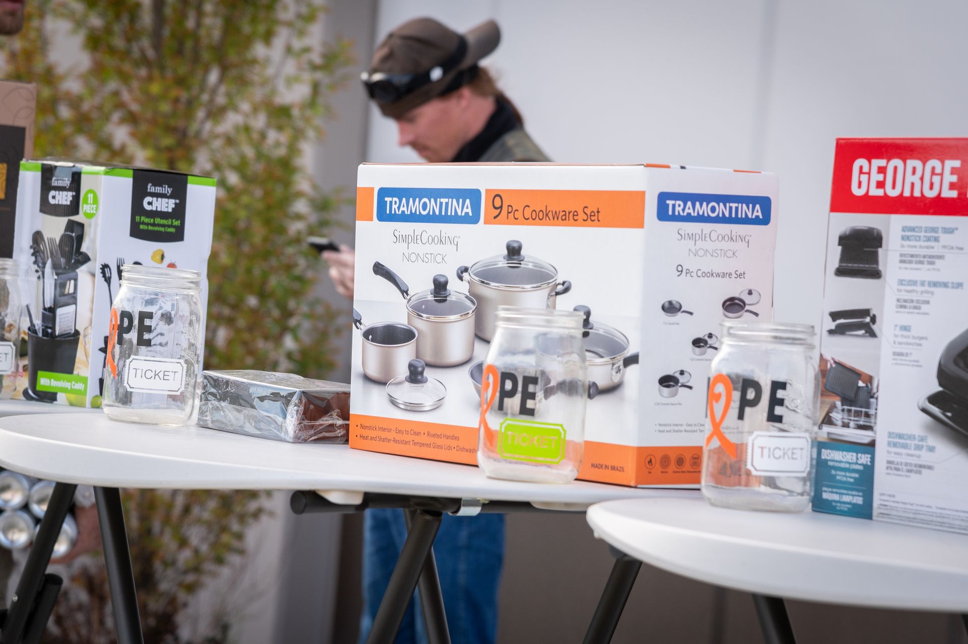 A man is standing behind a table with boxes of pots and pans on it.