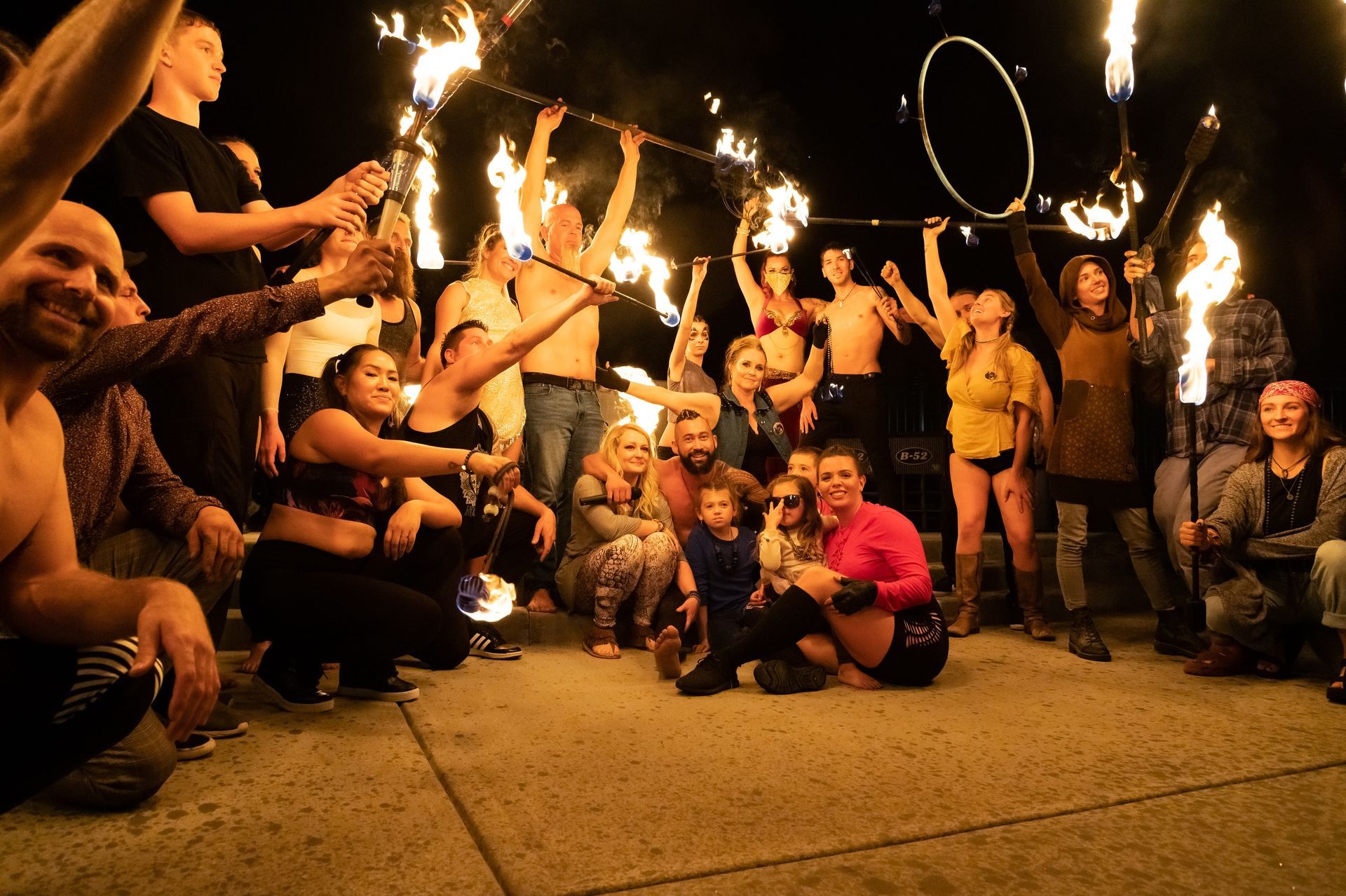 A group of people are posing for a picture with fire sticks.