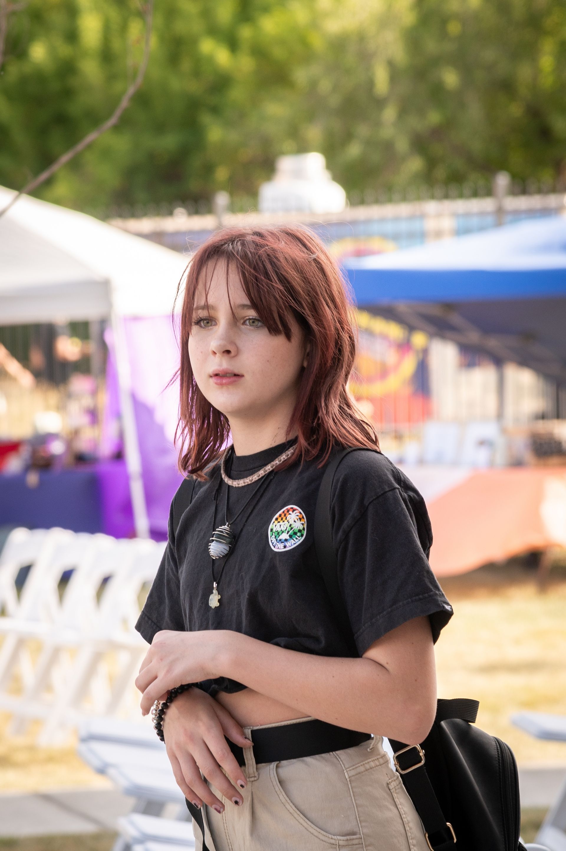 A young woman with red hair is standing in front of a tent.