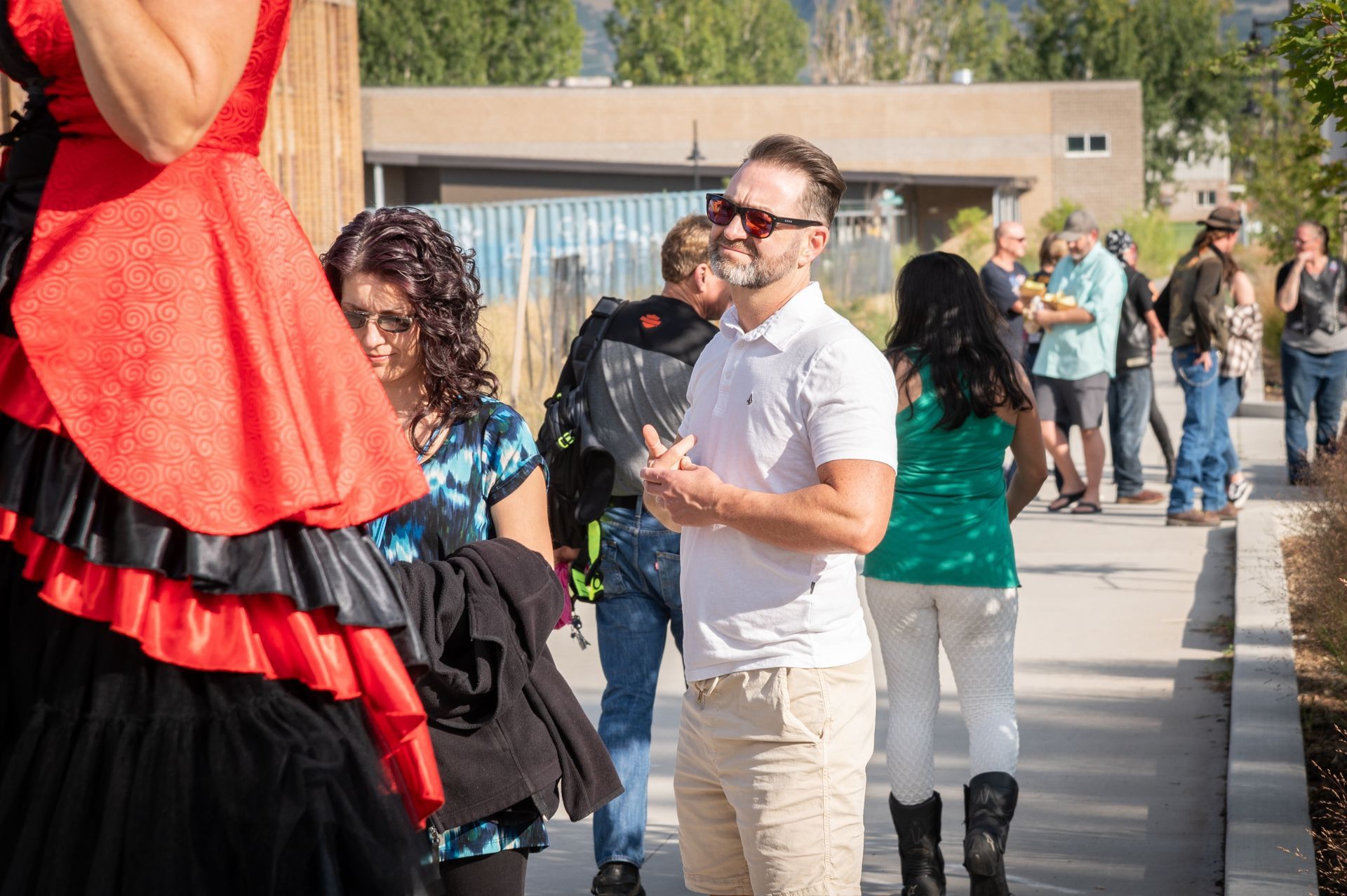 A man in a white shirt is standing next to a woman in a red dress on stilts.