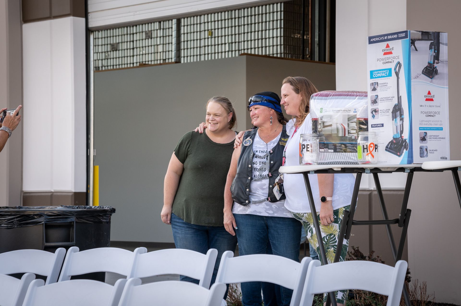 Three women are standing next to each other in front of a table.