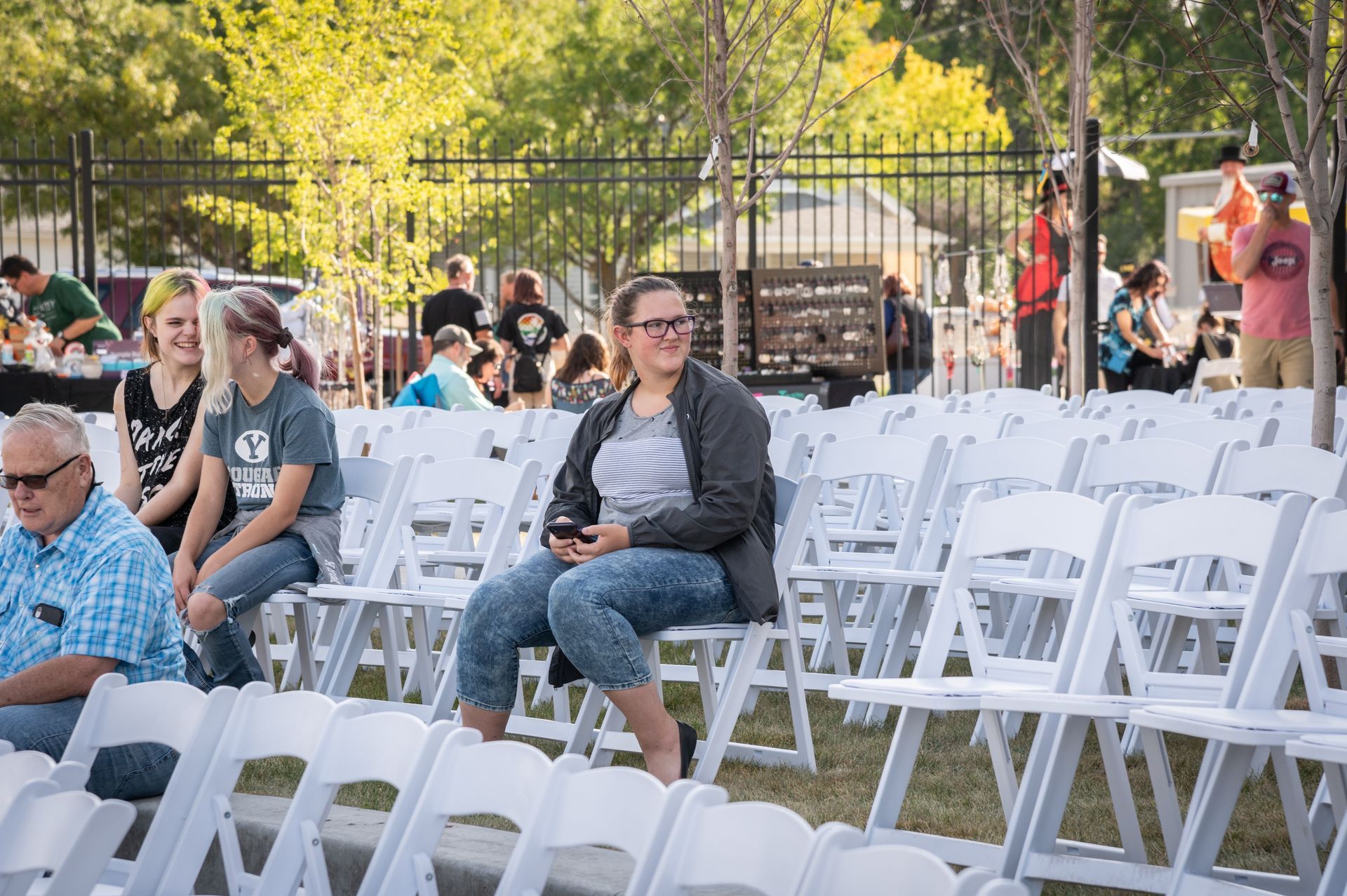 A woman is sitting in a row of white chairs.