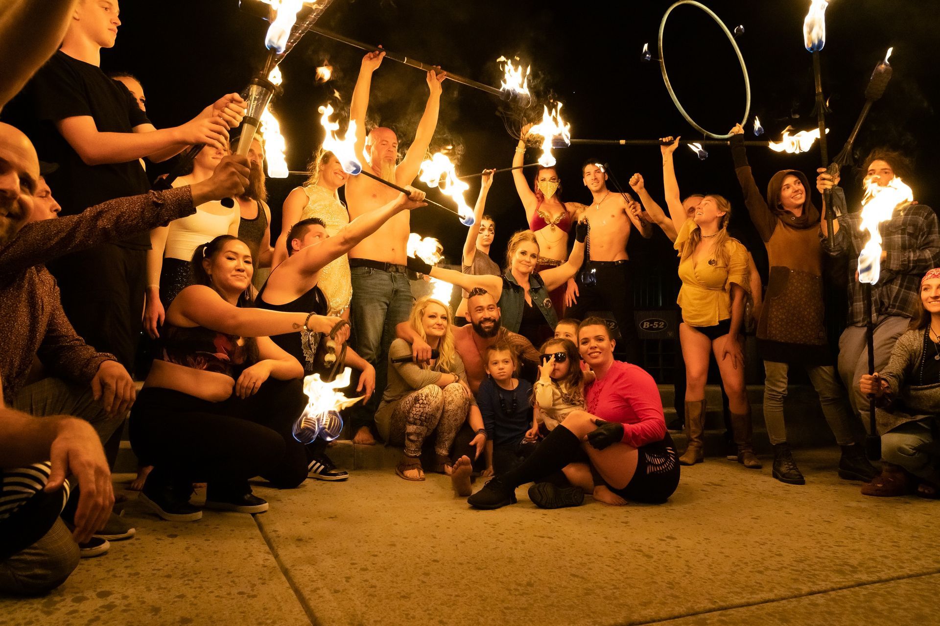 A group of people are posing for a picture while holding fire sticks.