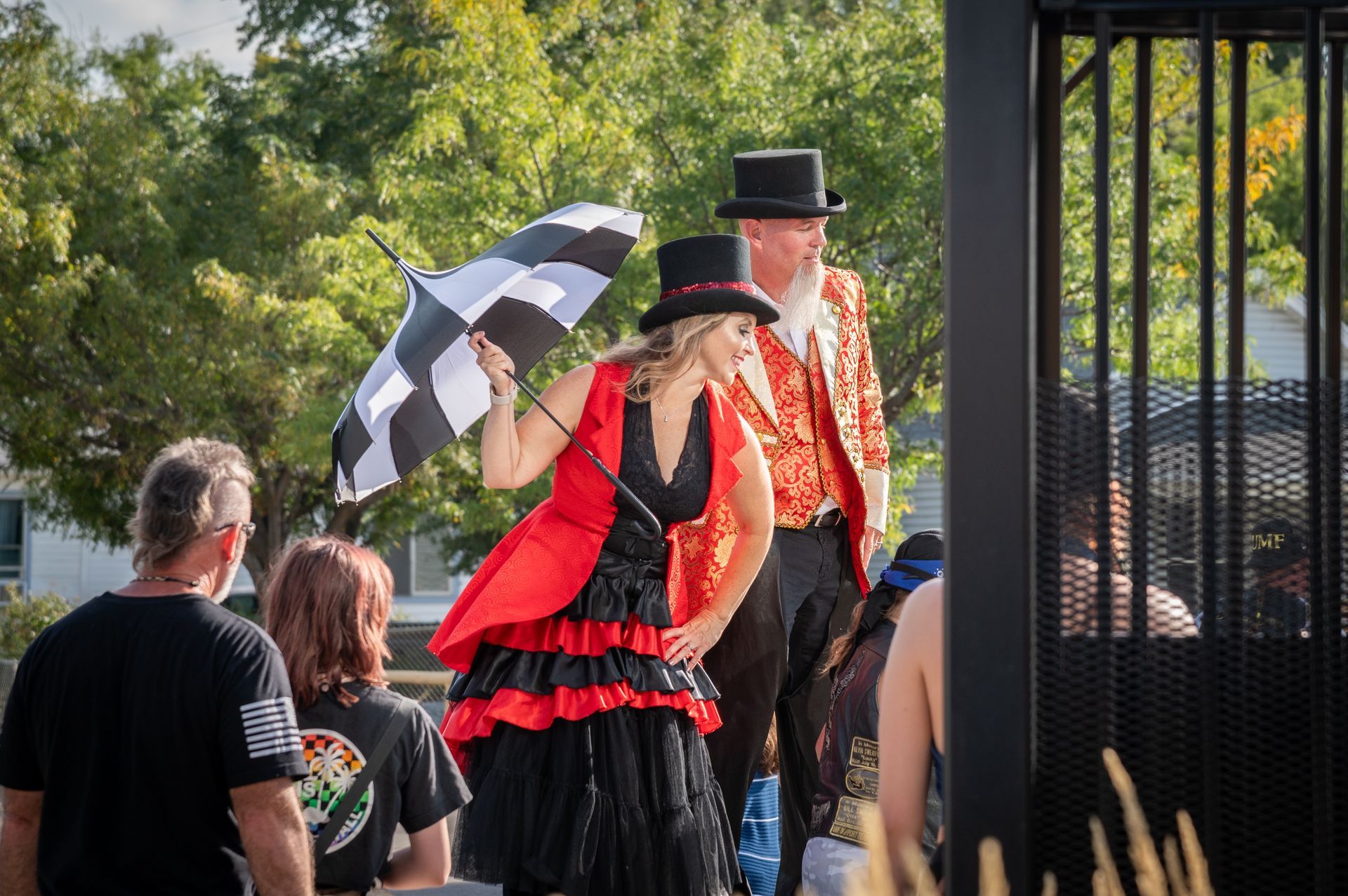A woman in a red dress is holding an umbrella next to a man in a top hat.
