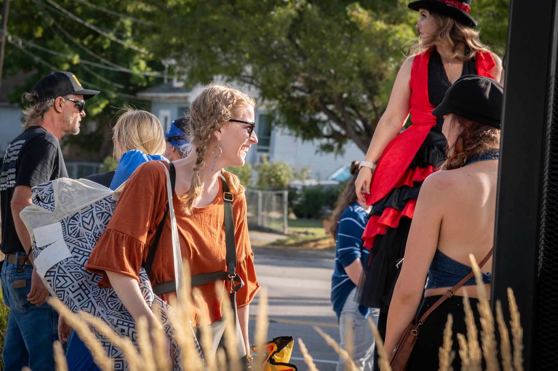 A group of people are standing on the side of the road talking to each other.