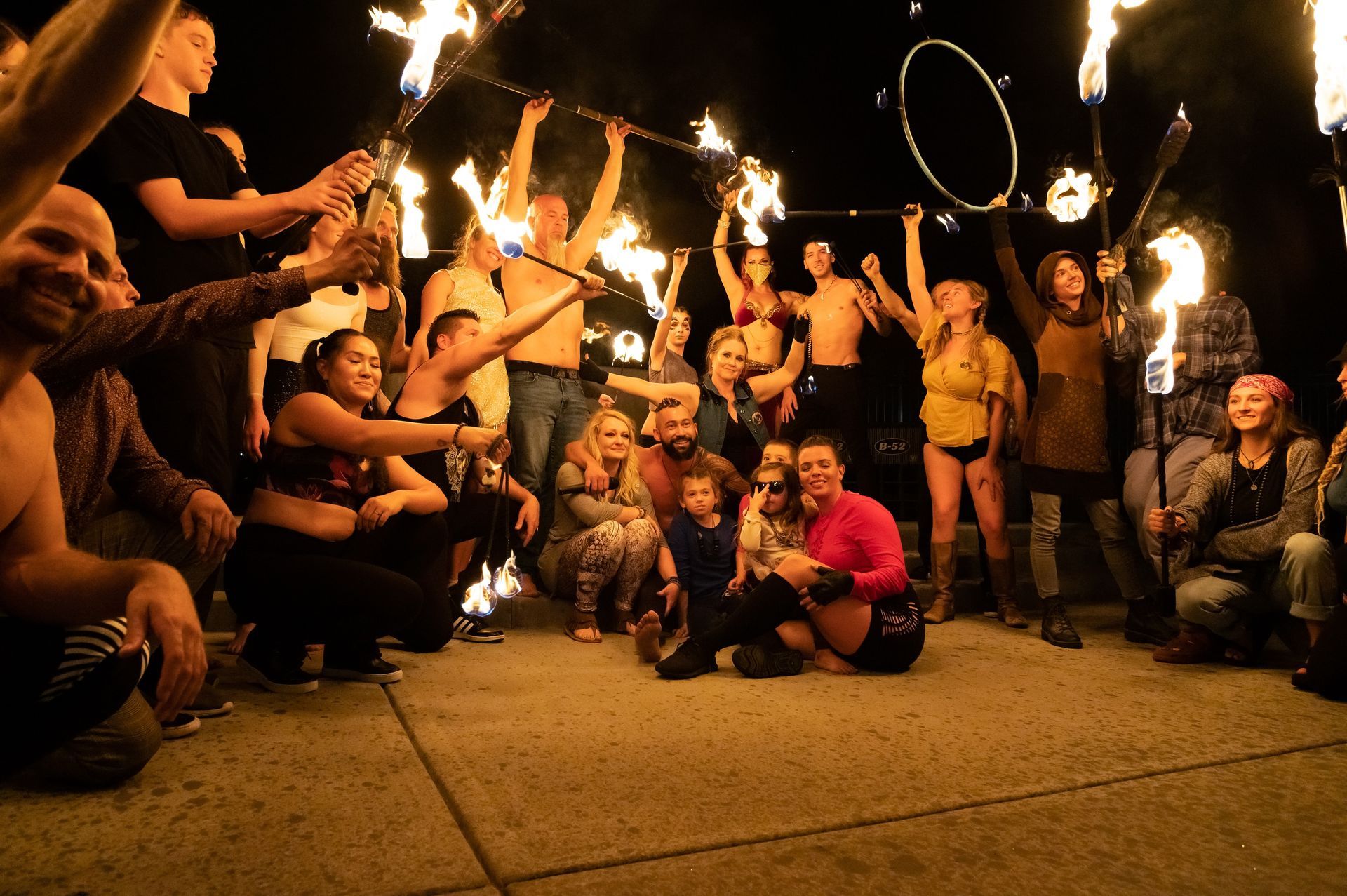 A group of people are posing for a picture while holding fire sticks.
