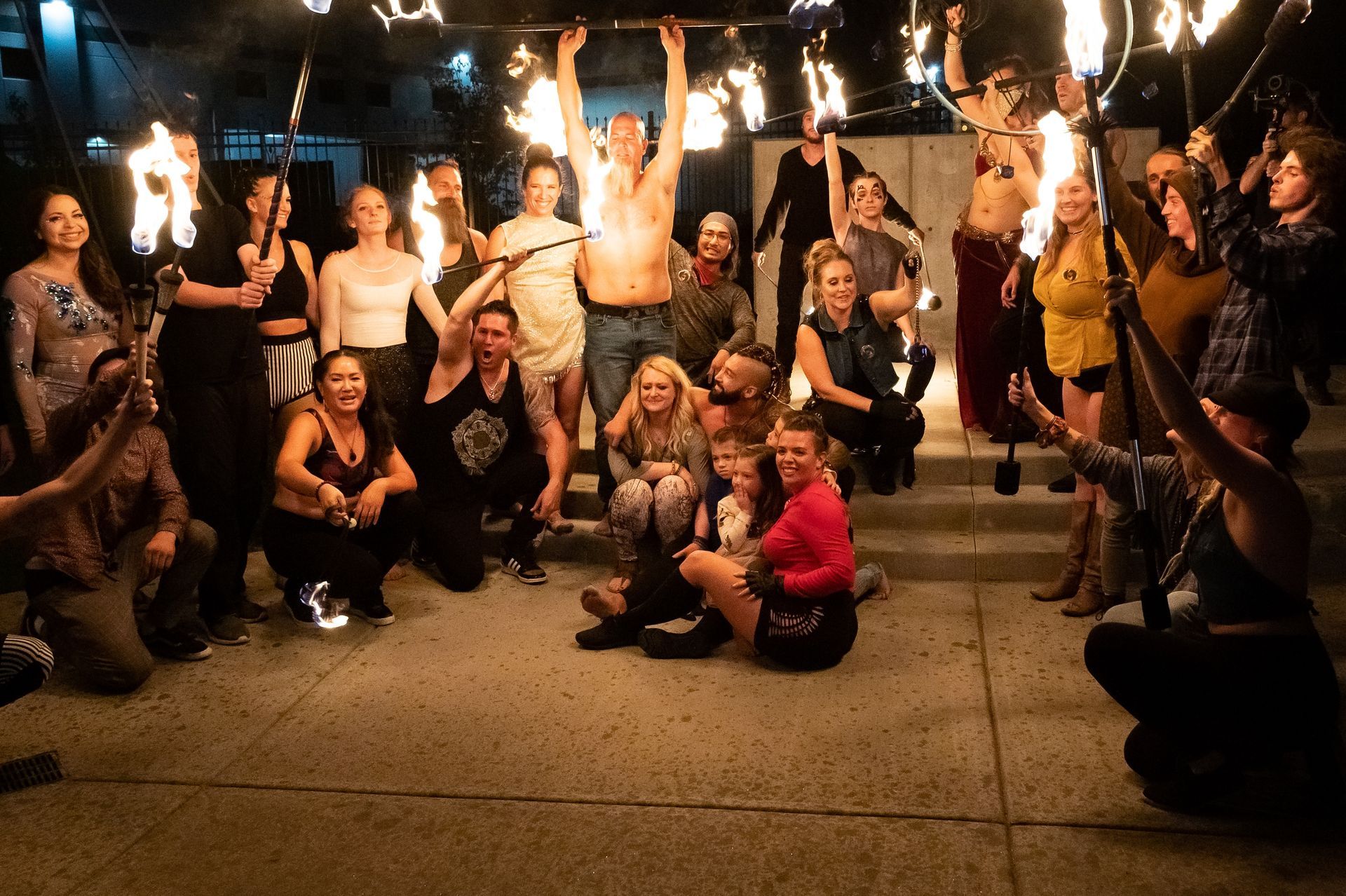 A group of people are posing for a picture while holding fire sticks.