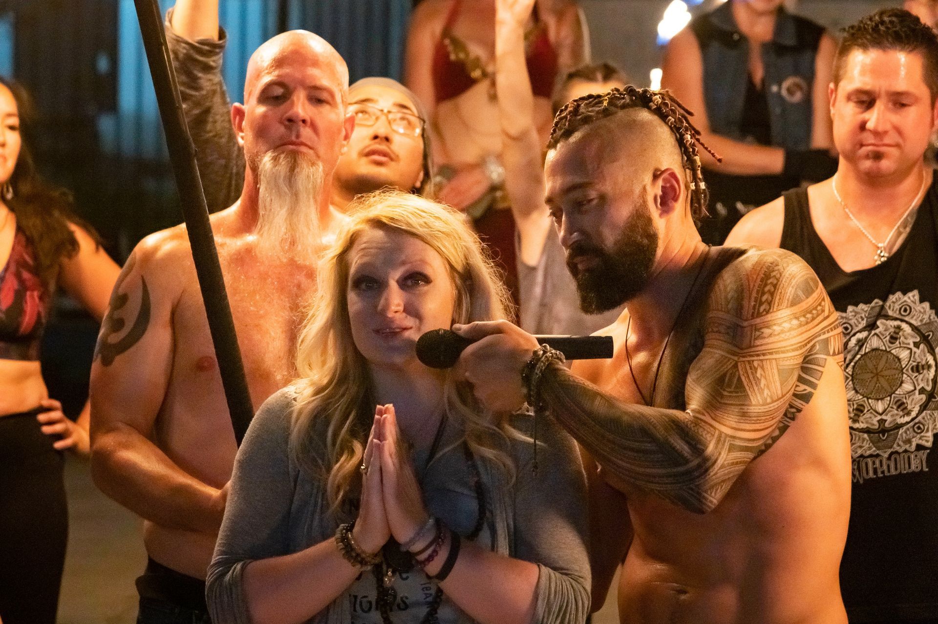 A group of people are standing around a man holding a microphone.