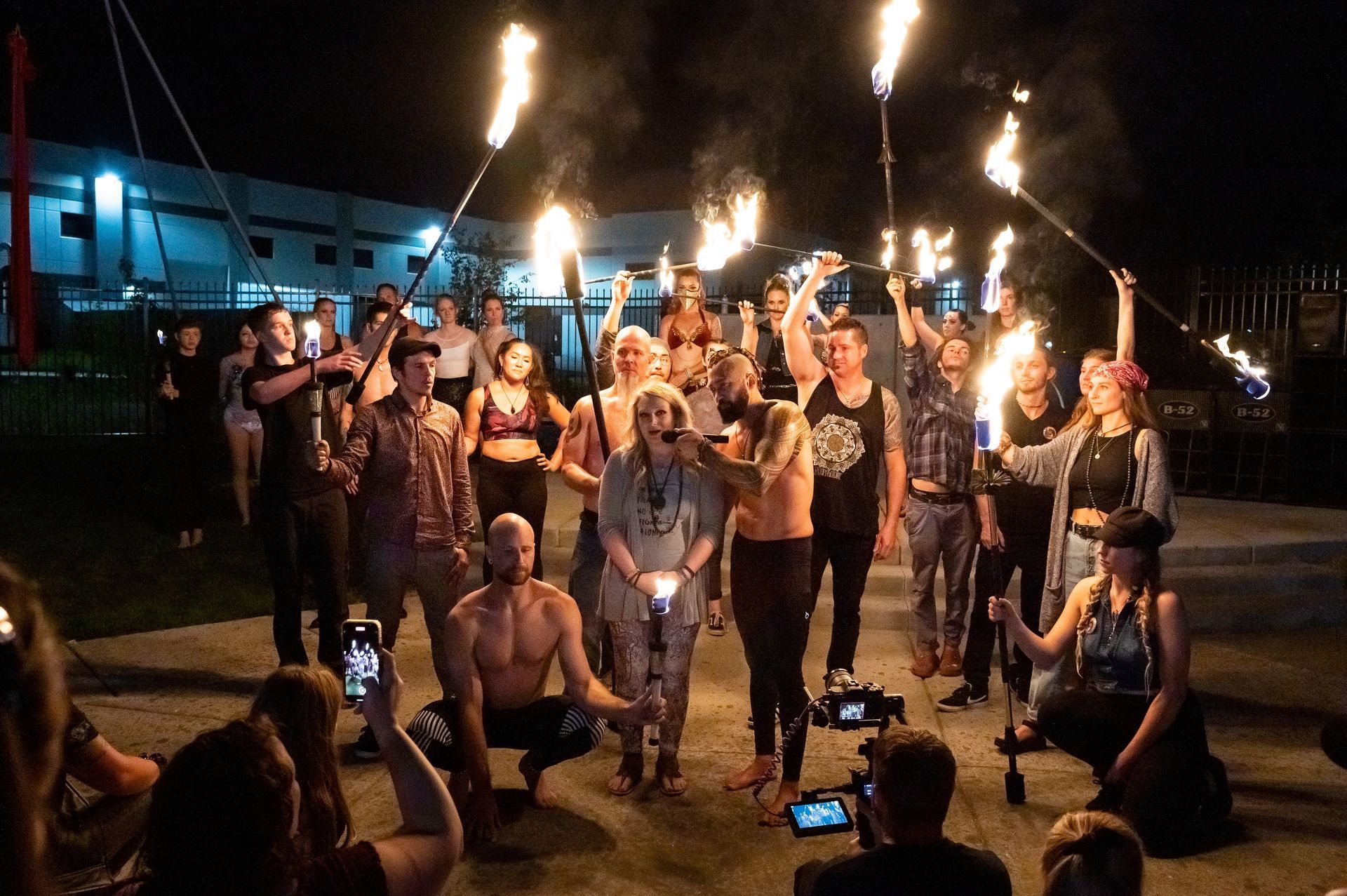 A group of people are holding fire torches in a circle at night.