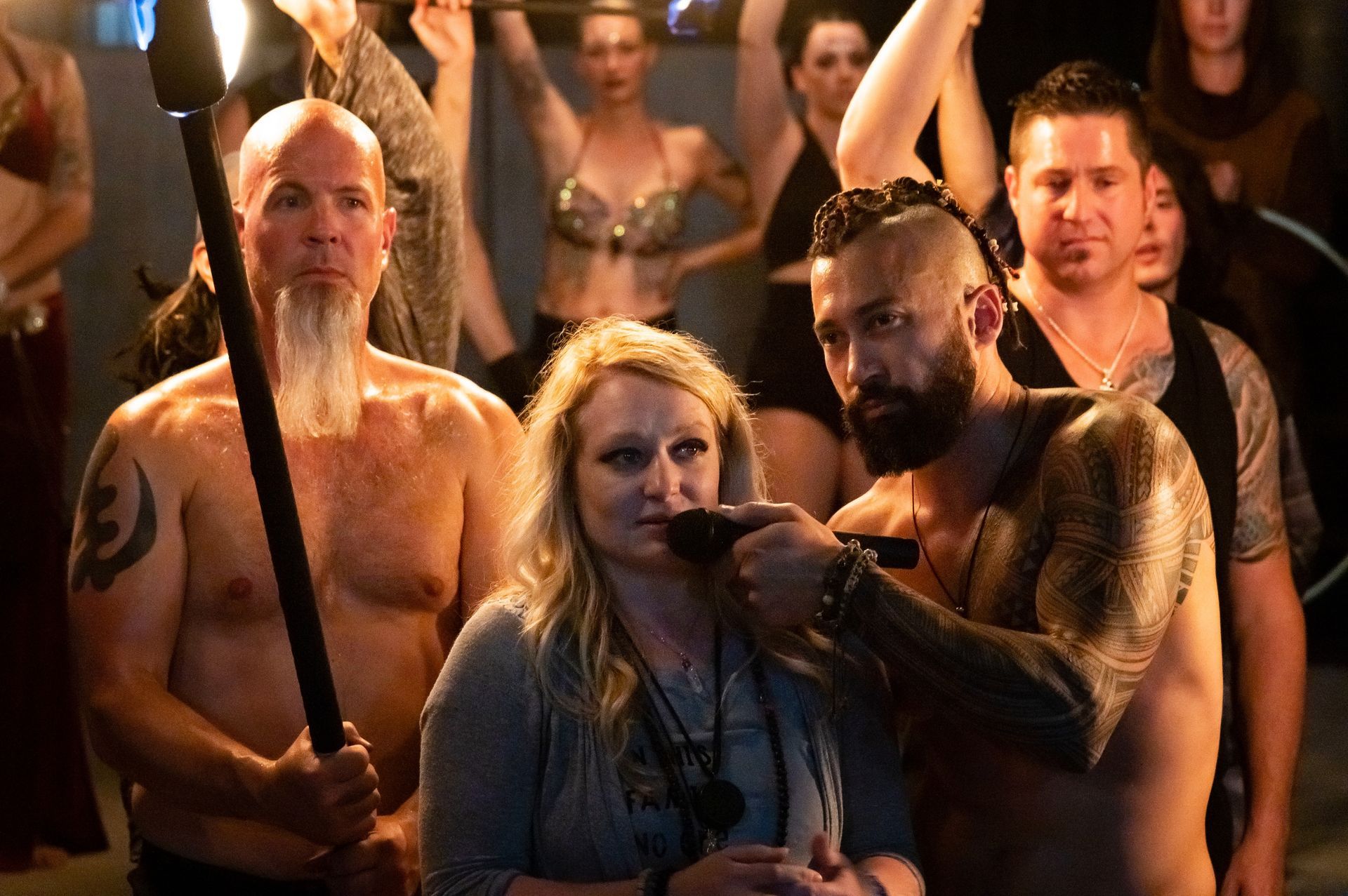 A group of people are standing in a dark room holding torches.