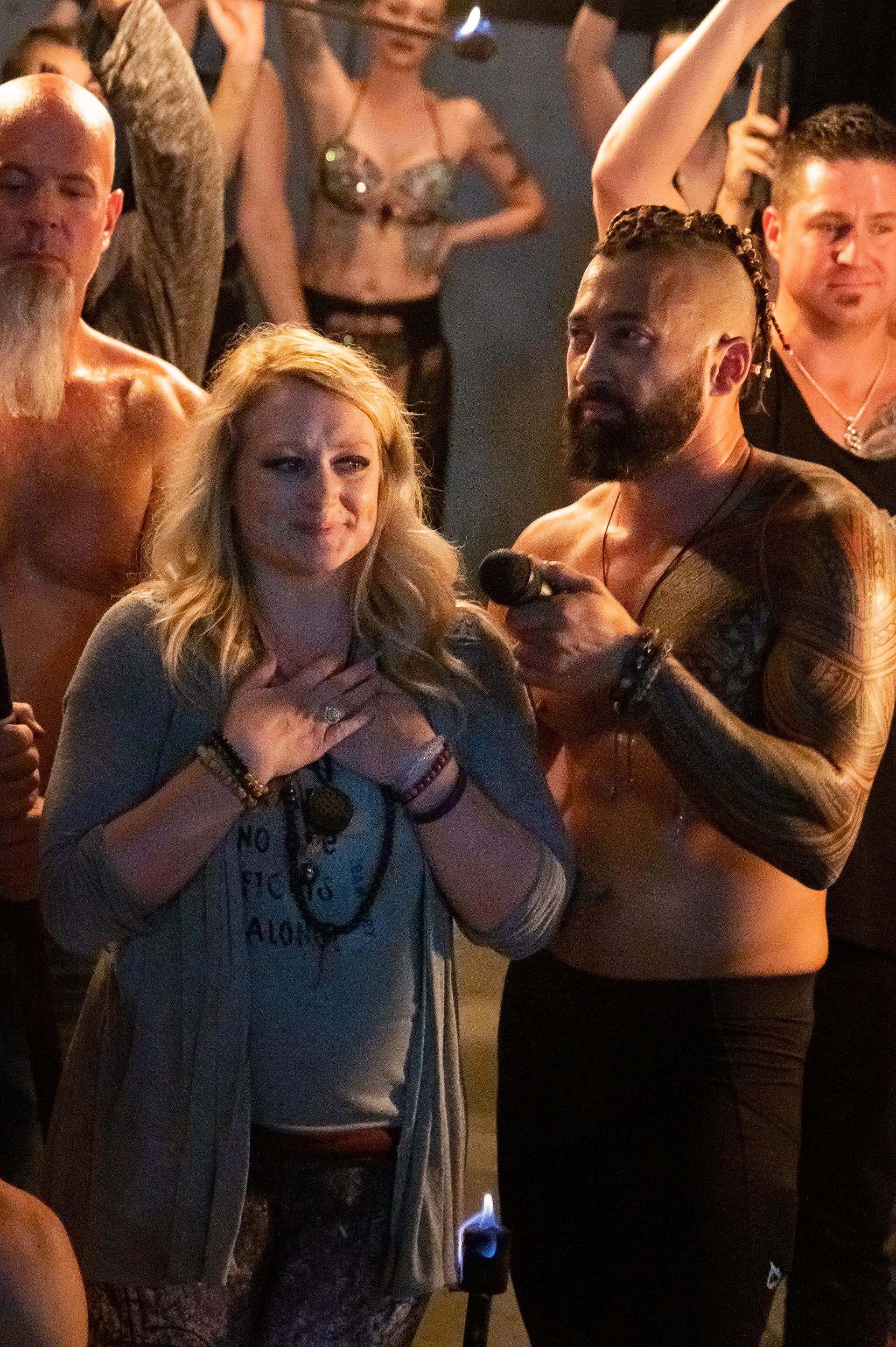 A group of people are standing in a room with their hands on their chests.