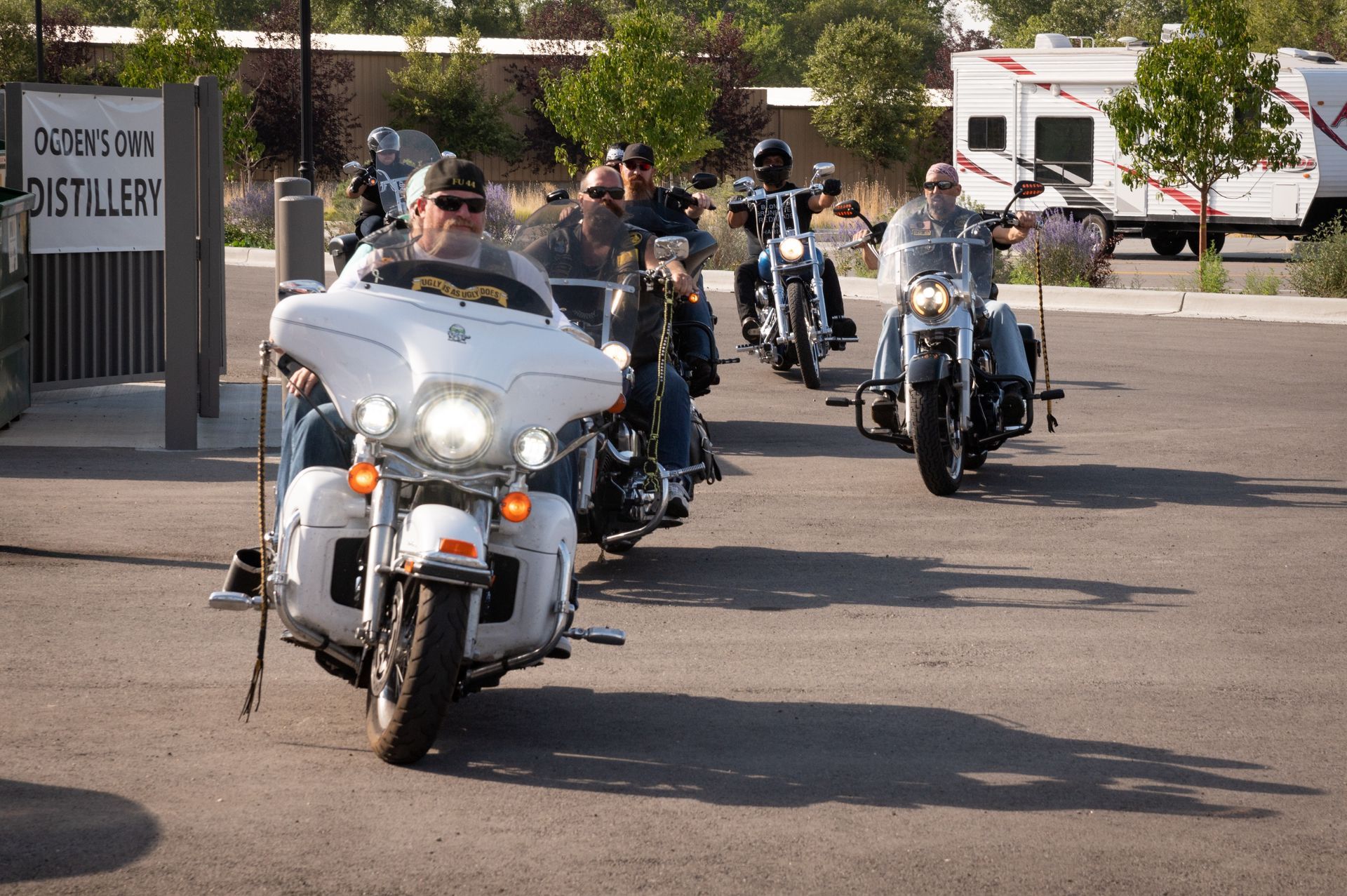 A group of people riding motorcycles in front of a sign that says distillery