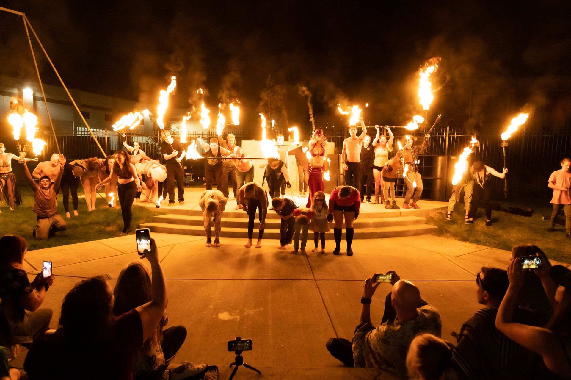 A crowd of people are watching a fire show at night.