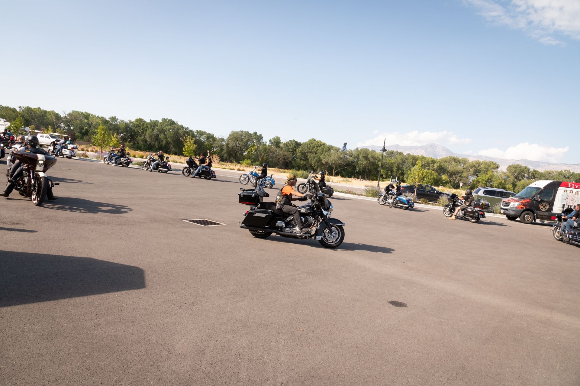 A group of people are riding motorcycles in a parking lot.