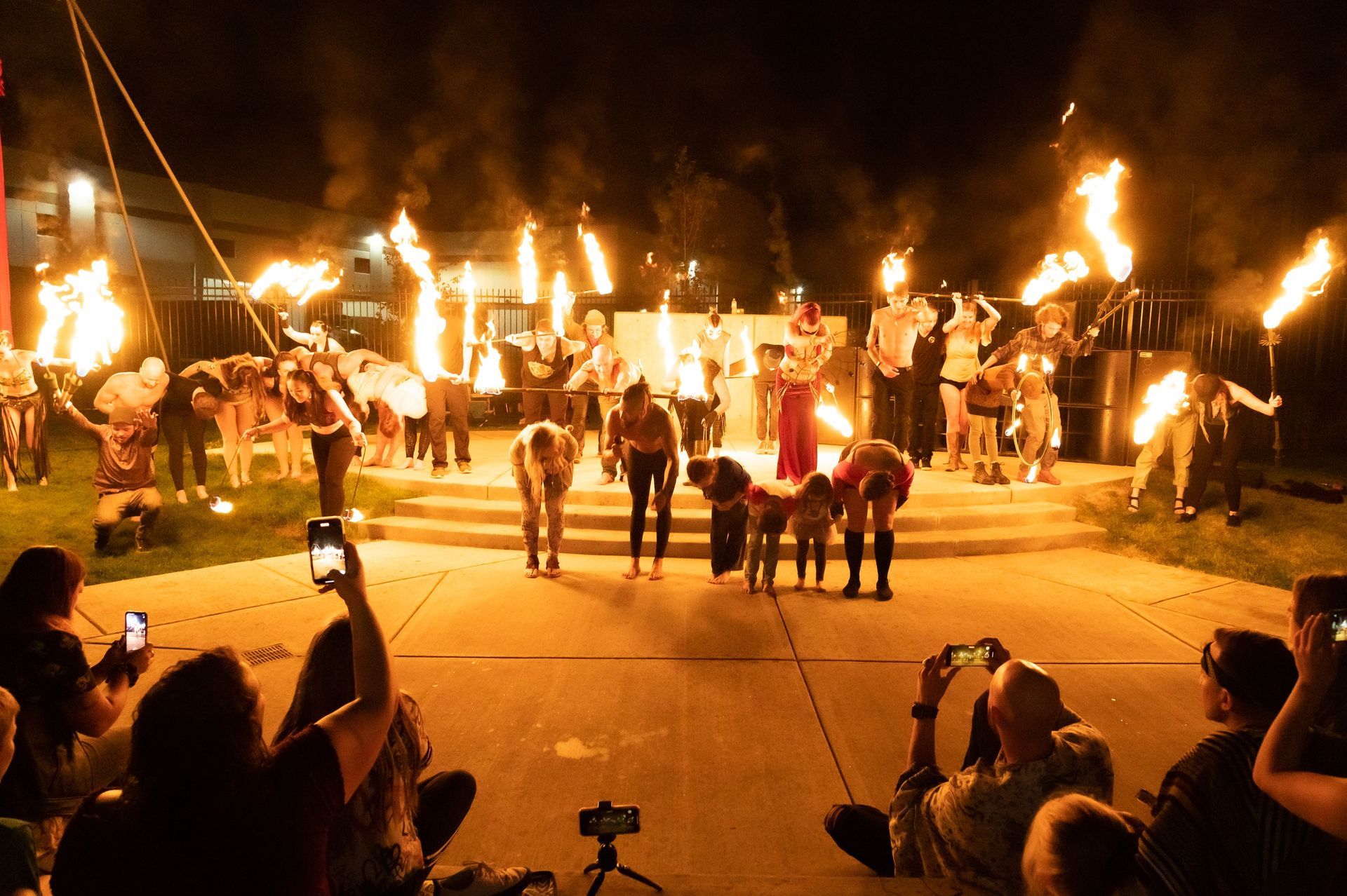 A crowd of people are watching a fire show at night.