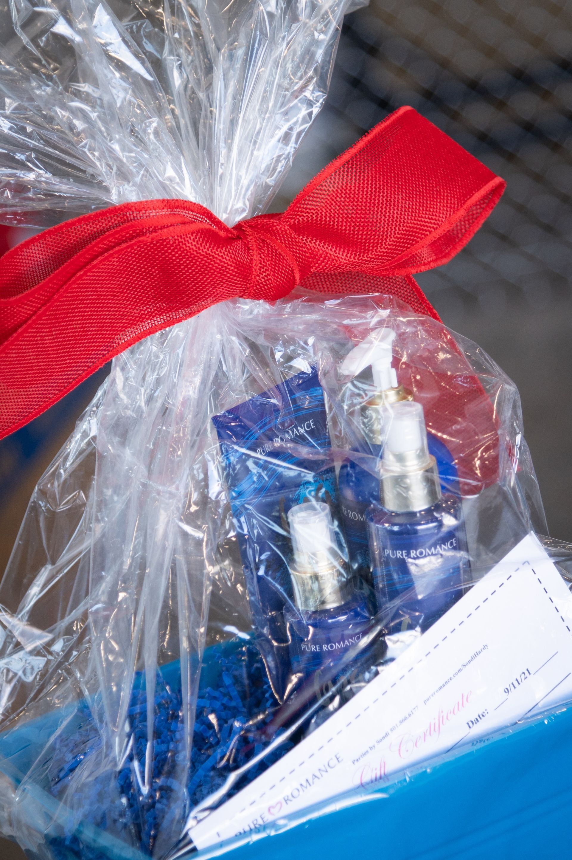 A gift wrapped in plastic with a red bow.