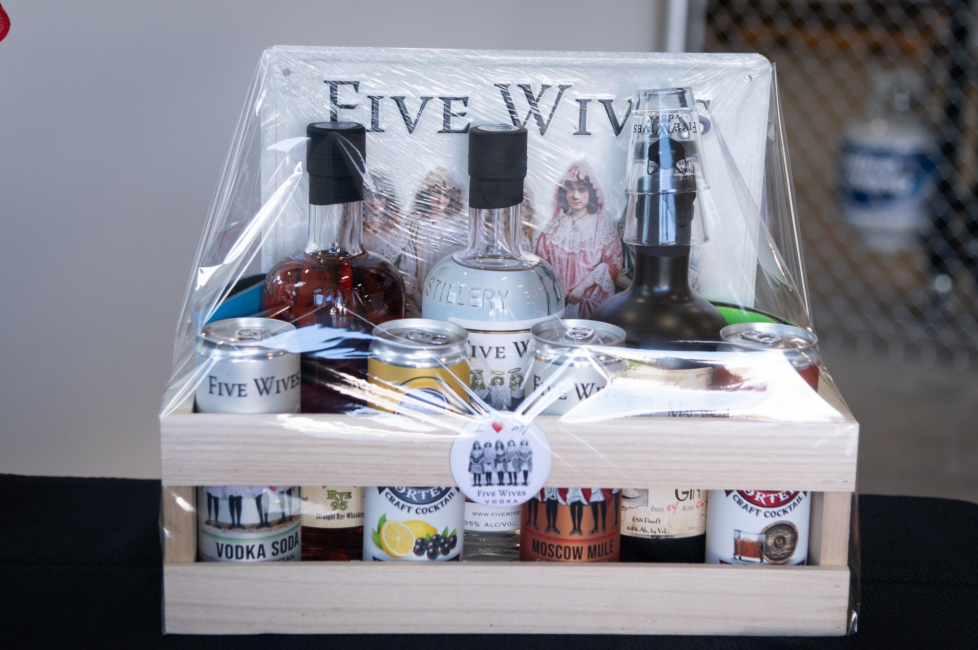 A wooden crate filled with bottles , cans , and a sign that says five wives.