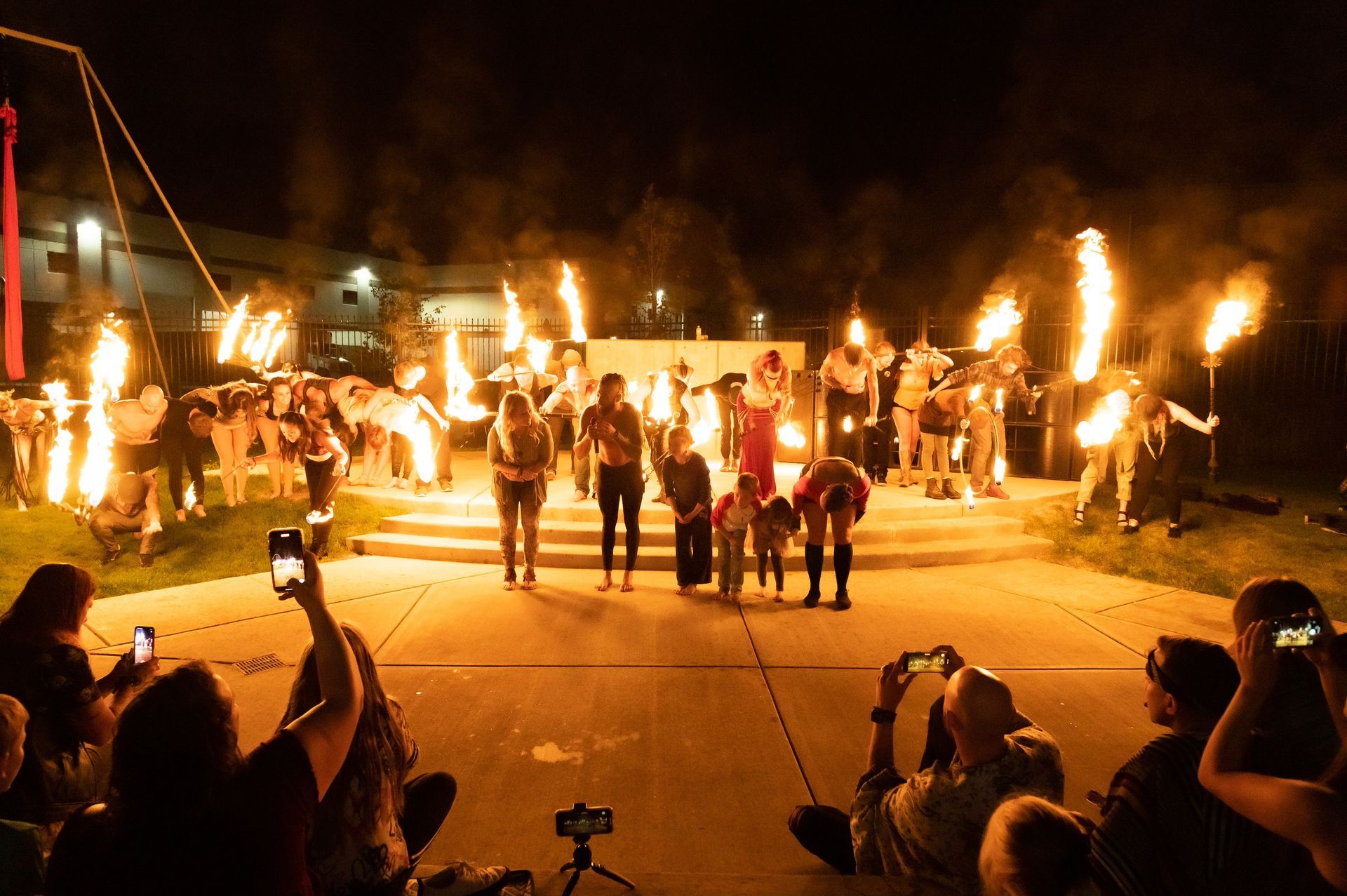 A crowd of people are watching a fire show at night.