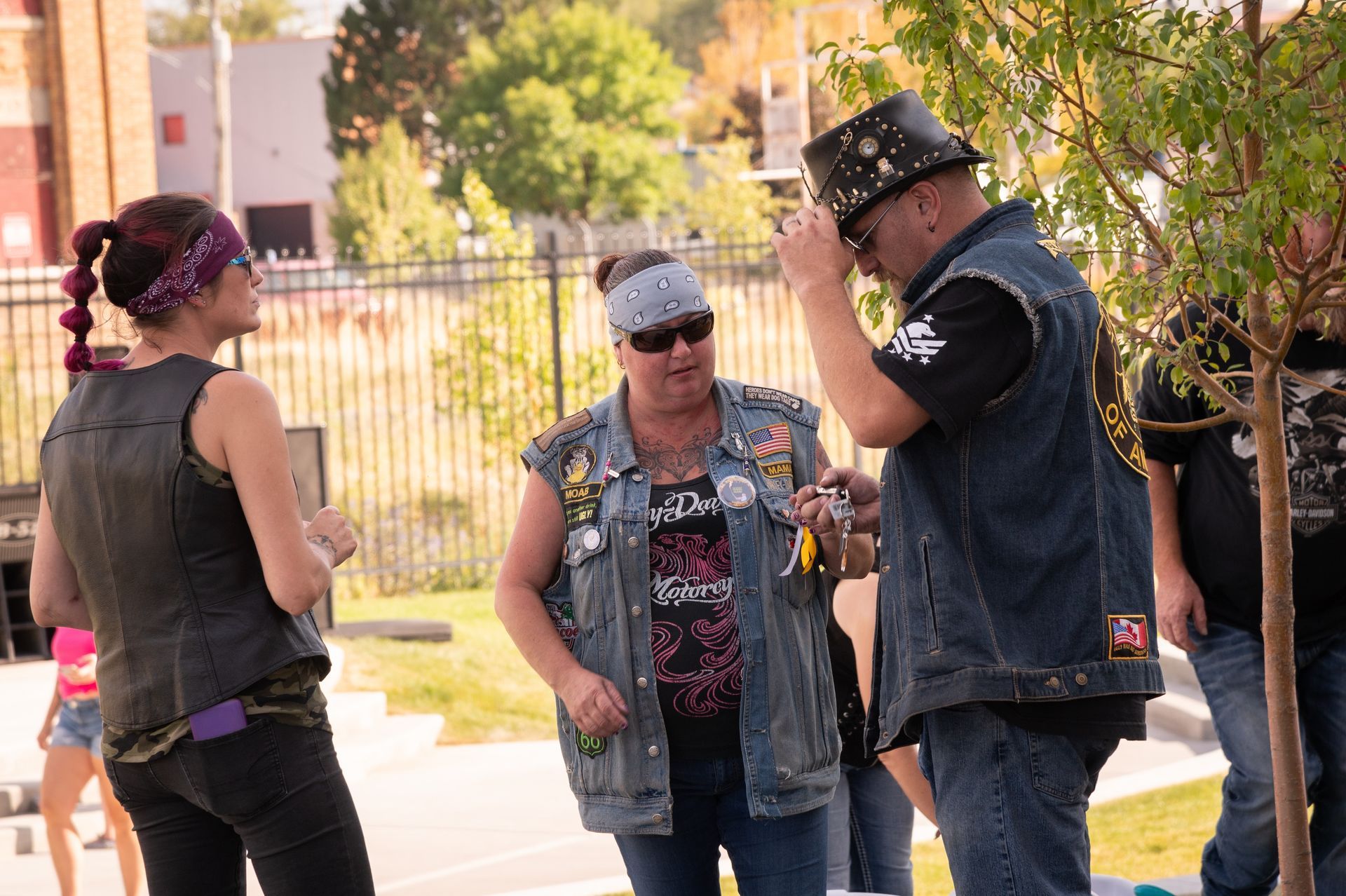 A group of people are standing in a park talking to each other.