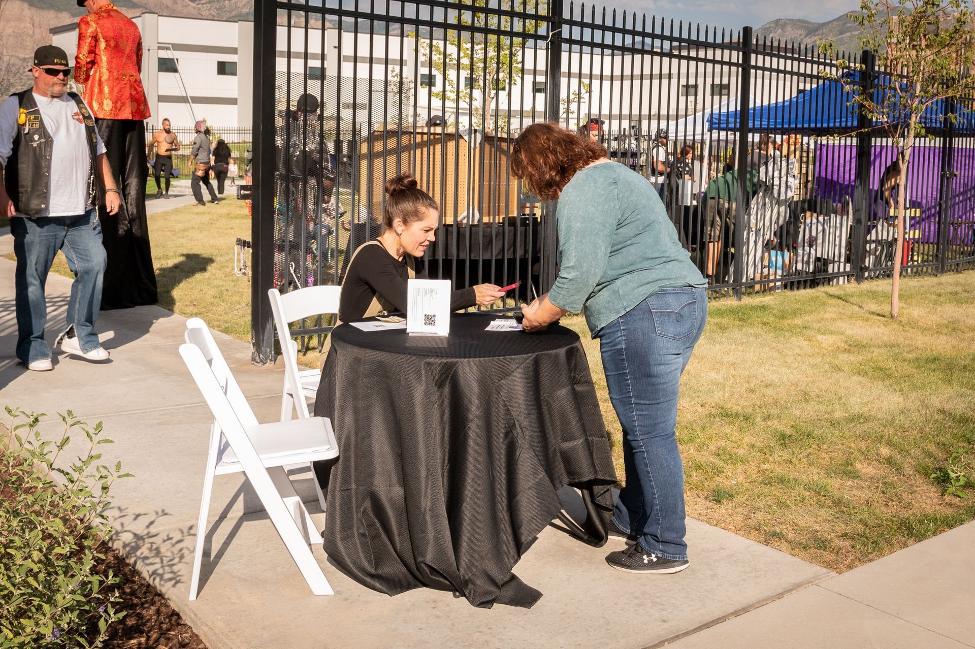 A woman is standing next to a girl sitting at a table.