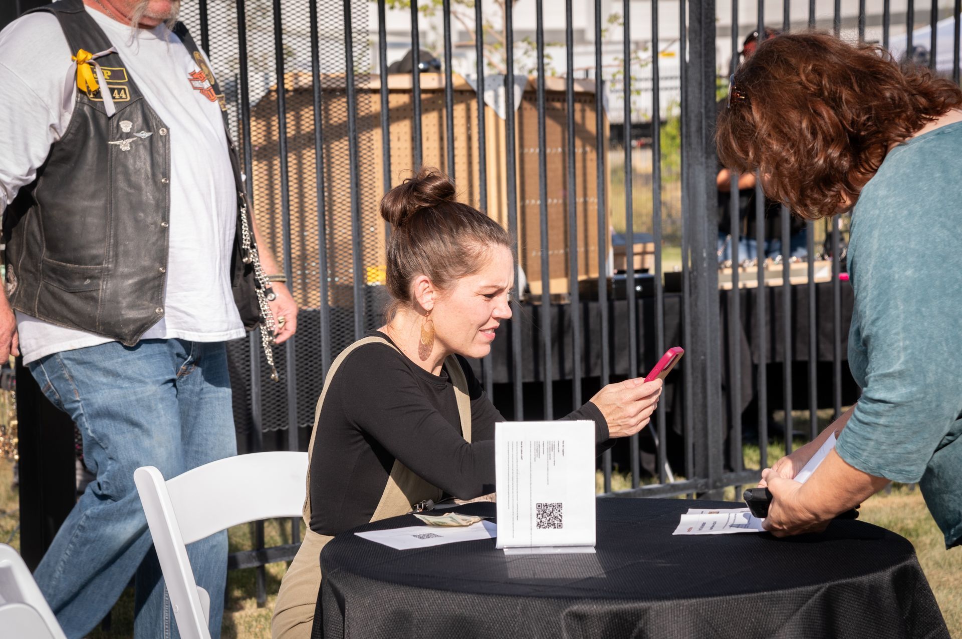 A woman is sitting at a table looking at her phone.