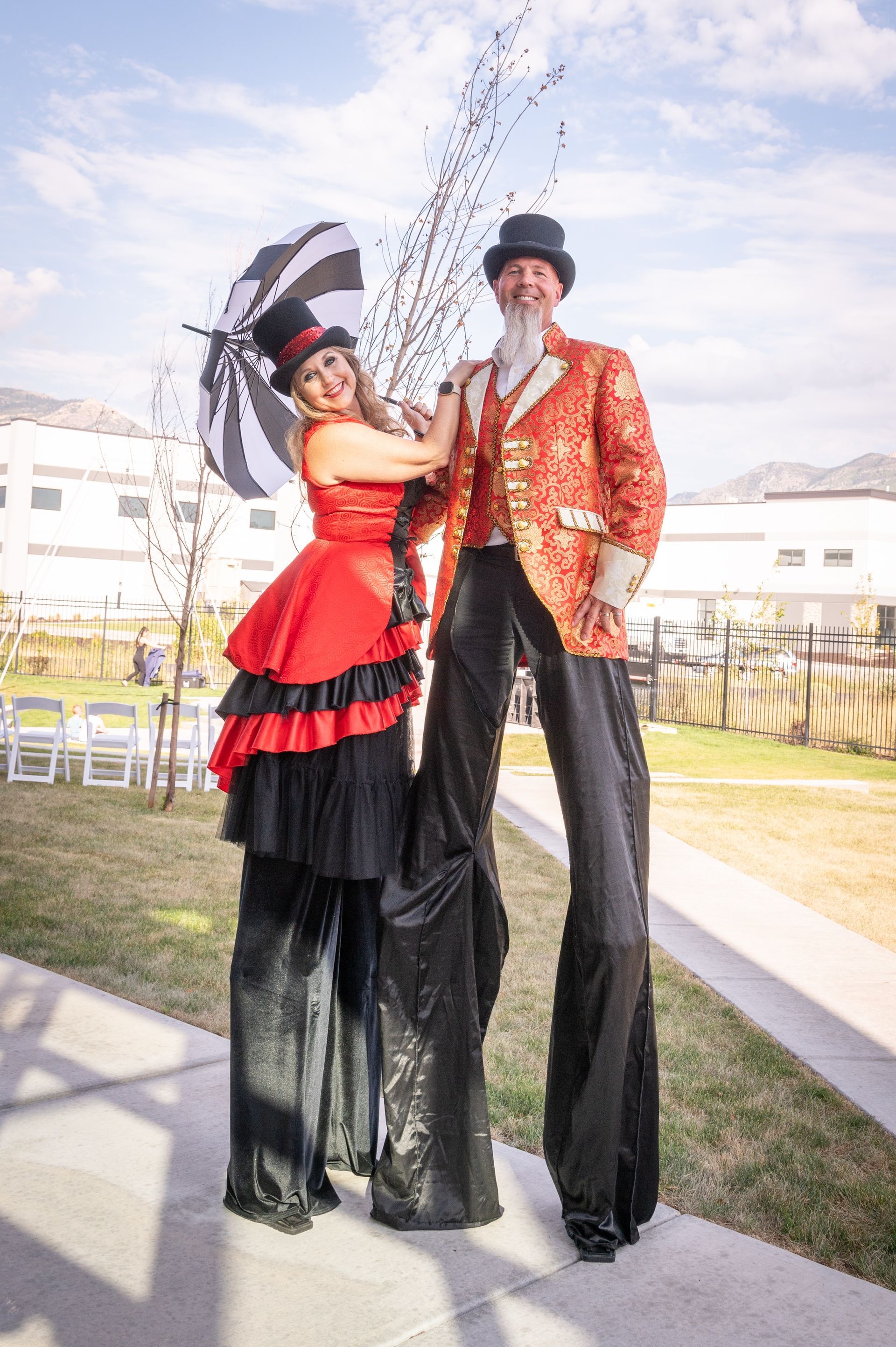 A man and a woman are standing on stilts on a sidewalk.