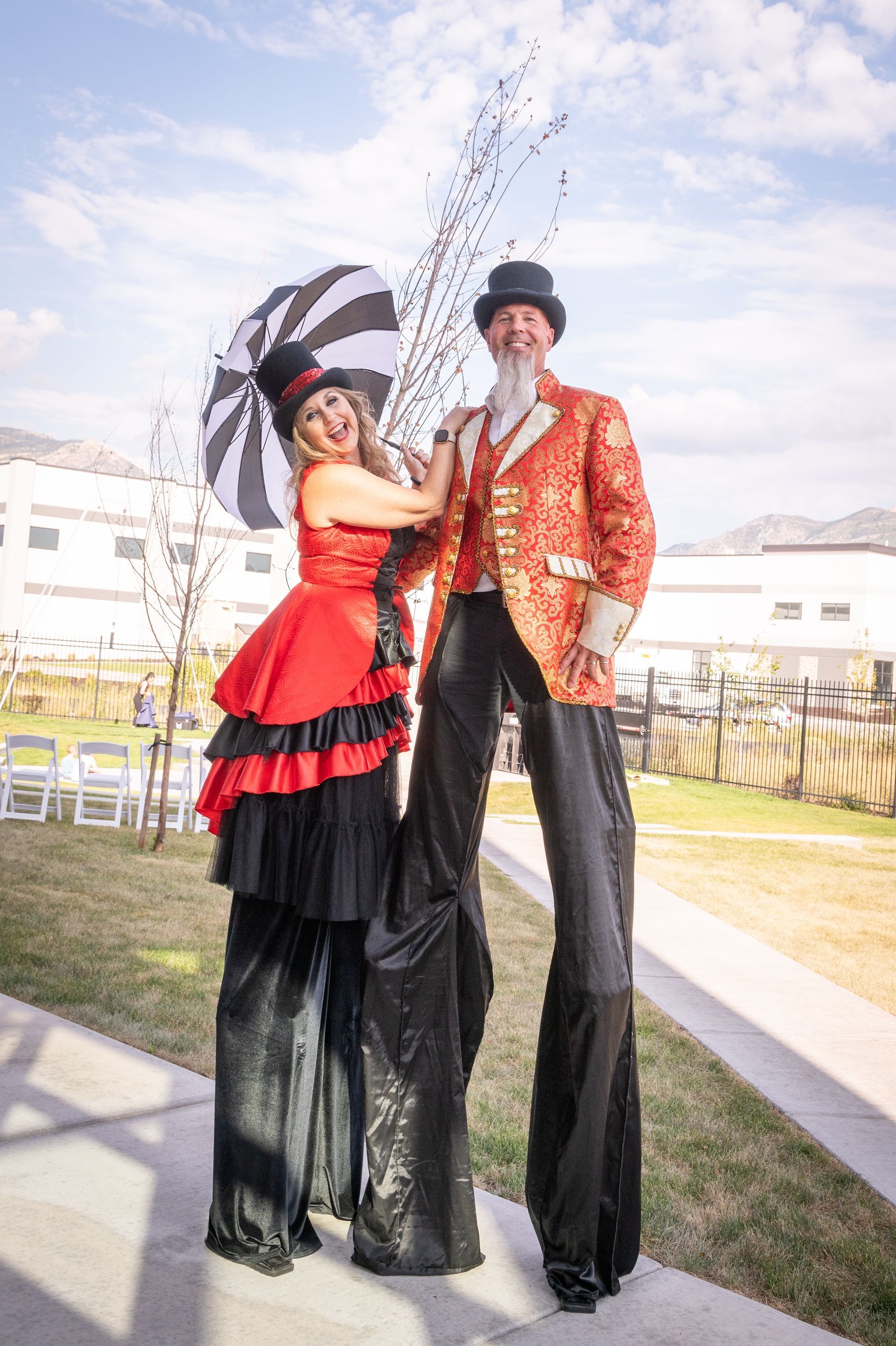 A man and a woman are standing on stilts and throwing confetti.