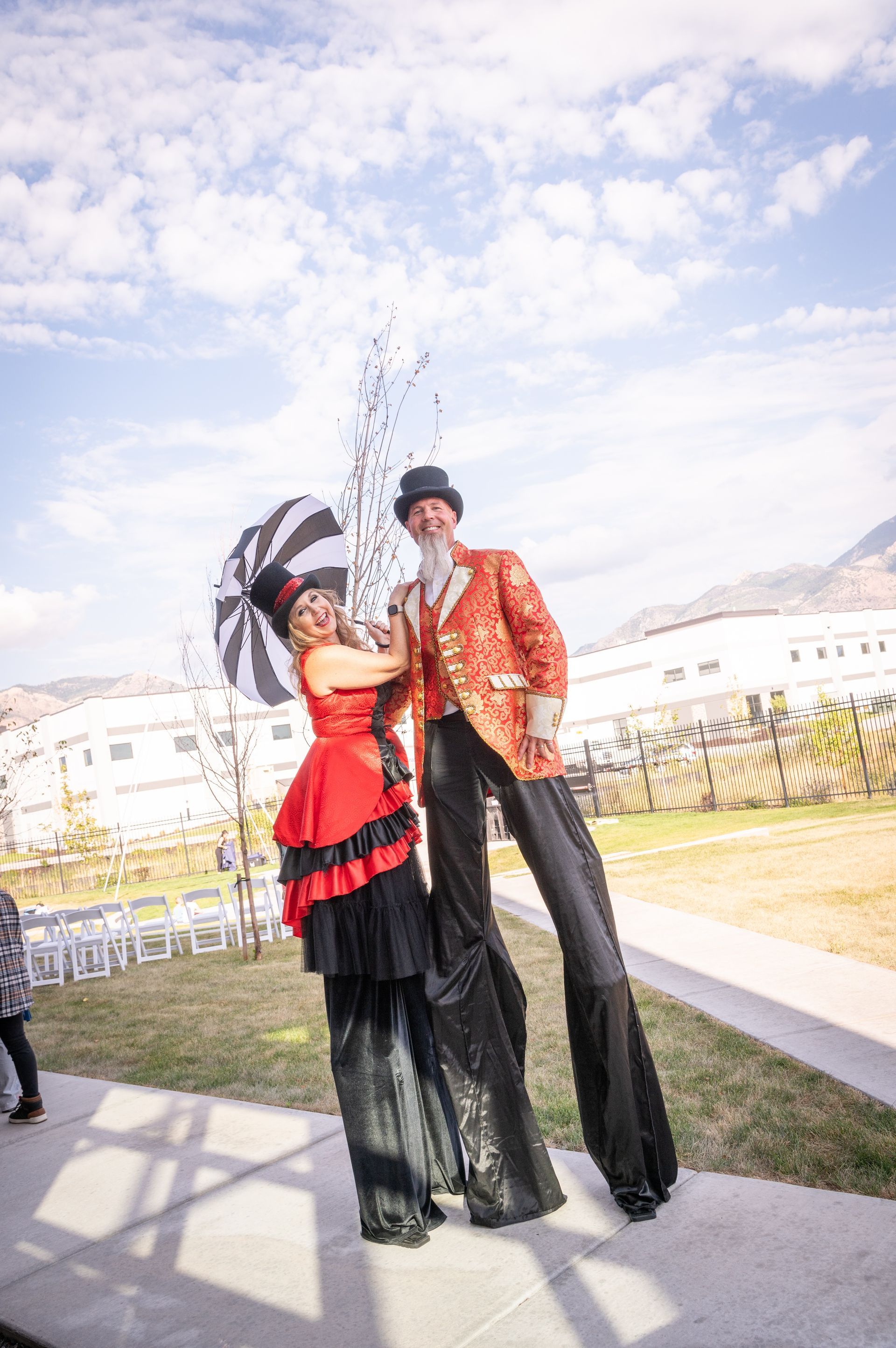 A man and a woman on stilts are standing next to each other on a sidewalk.