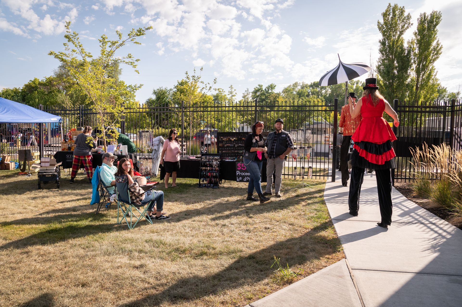 A woman in a red dress is walking down a sidewalk in a park.