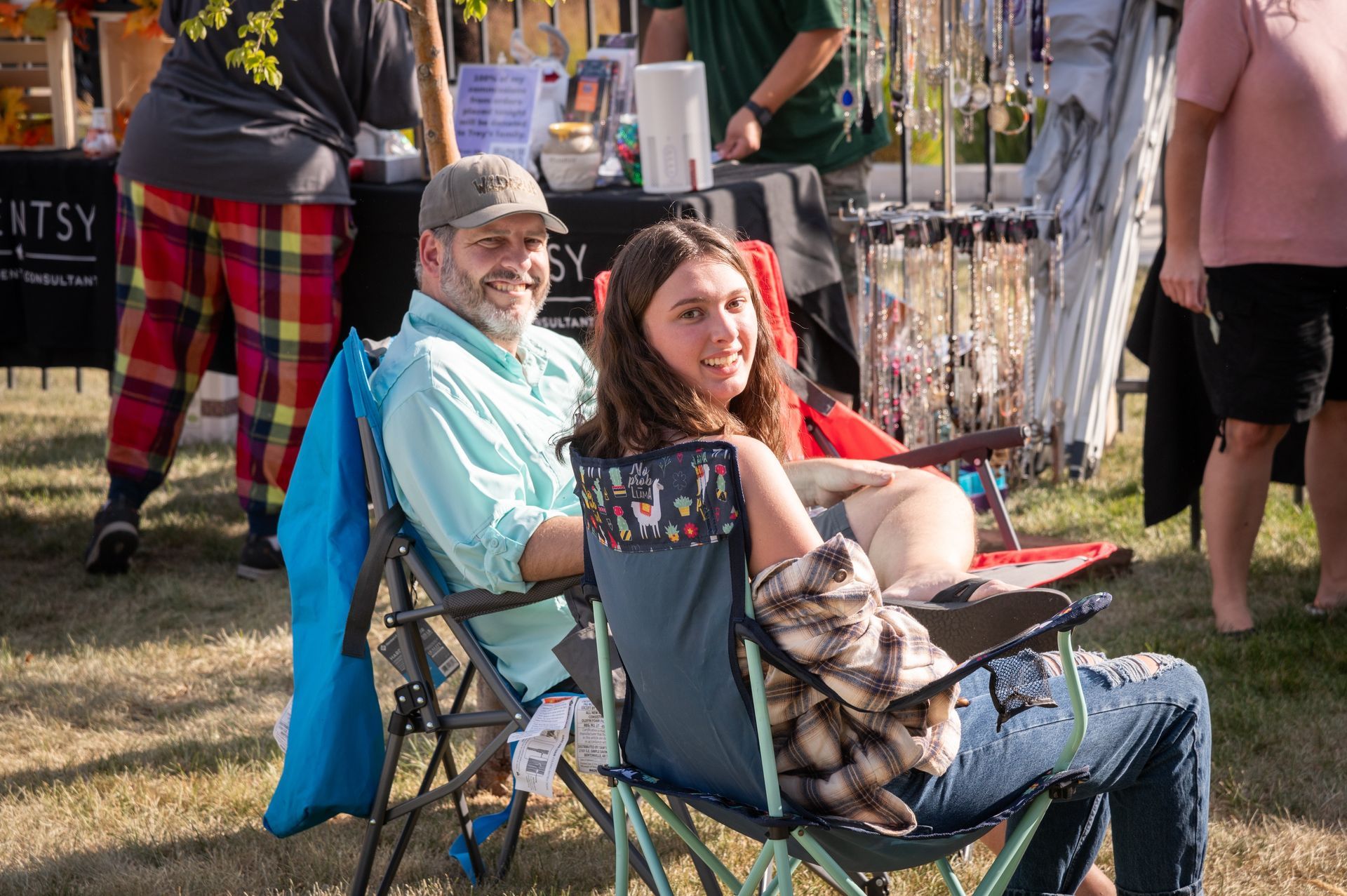 A man and a woman are sitting in folding chairs at a festival.