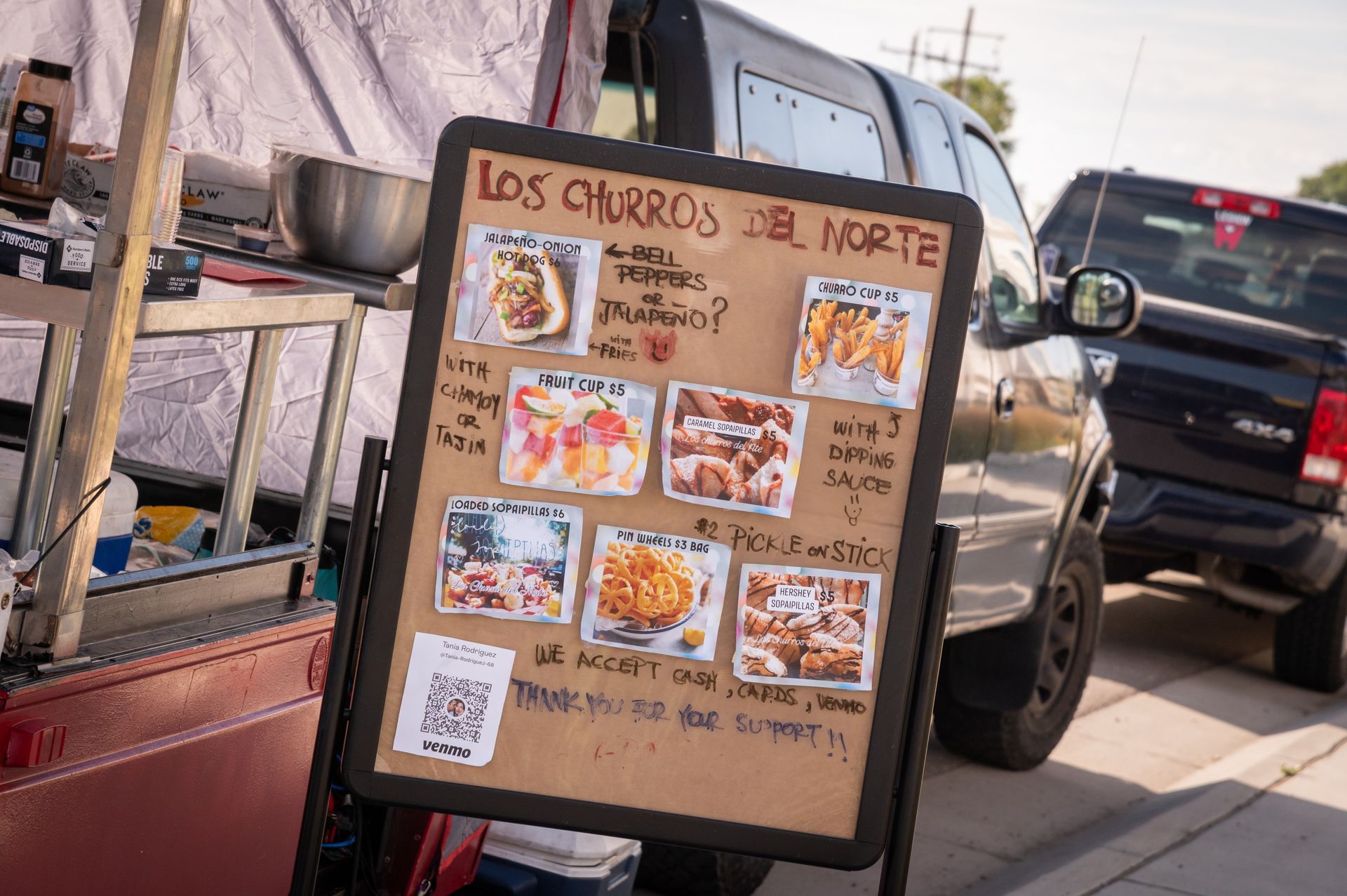 A sign for los churros del norte is sitting next to a truck.