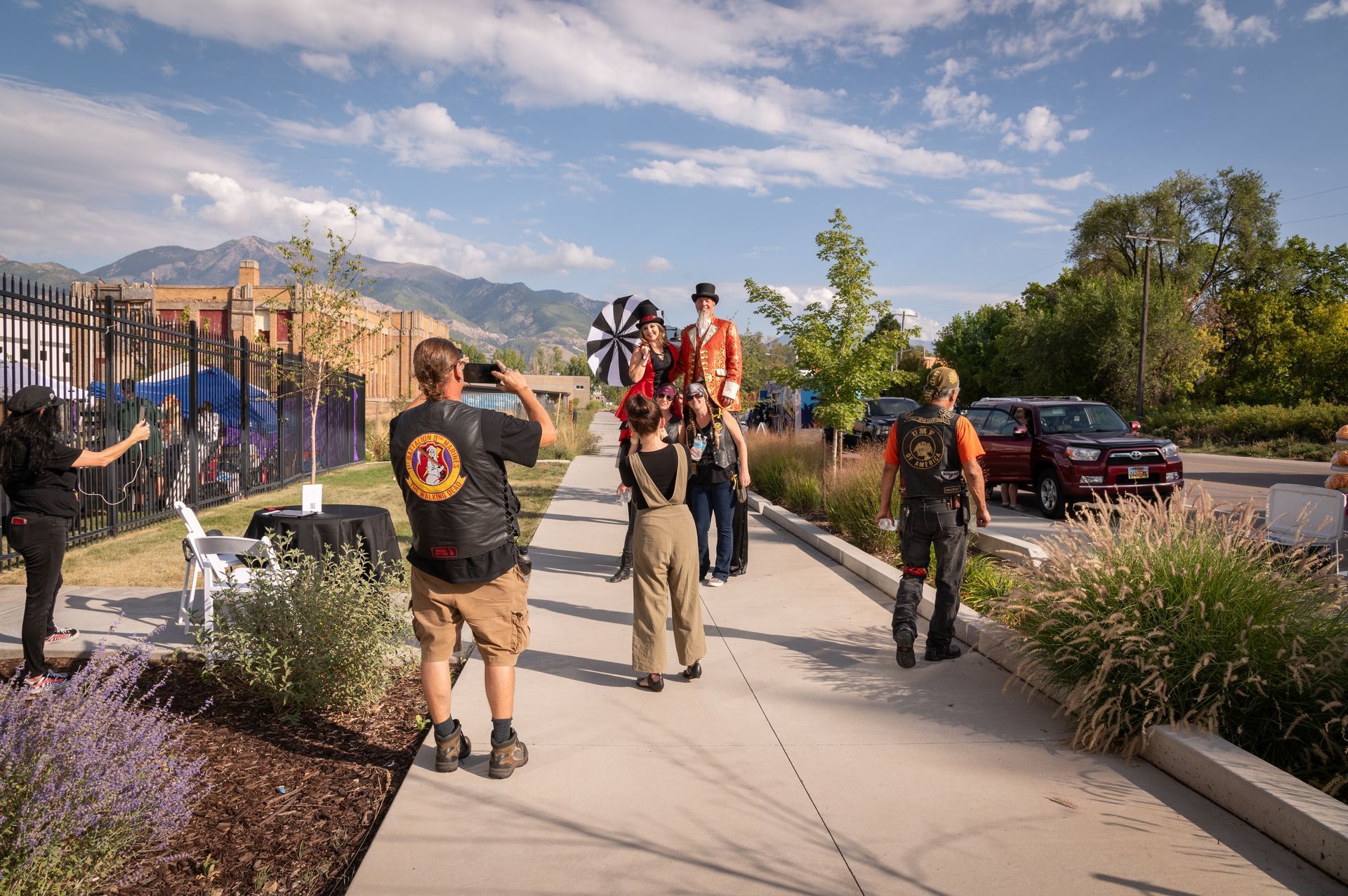 A group of people are standing on a sidewalk.