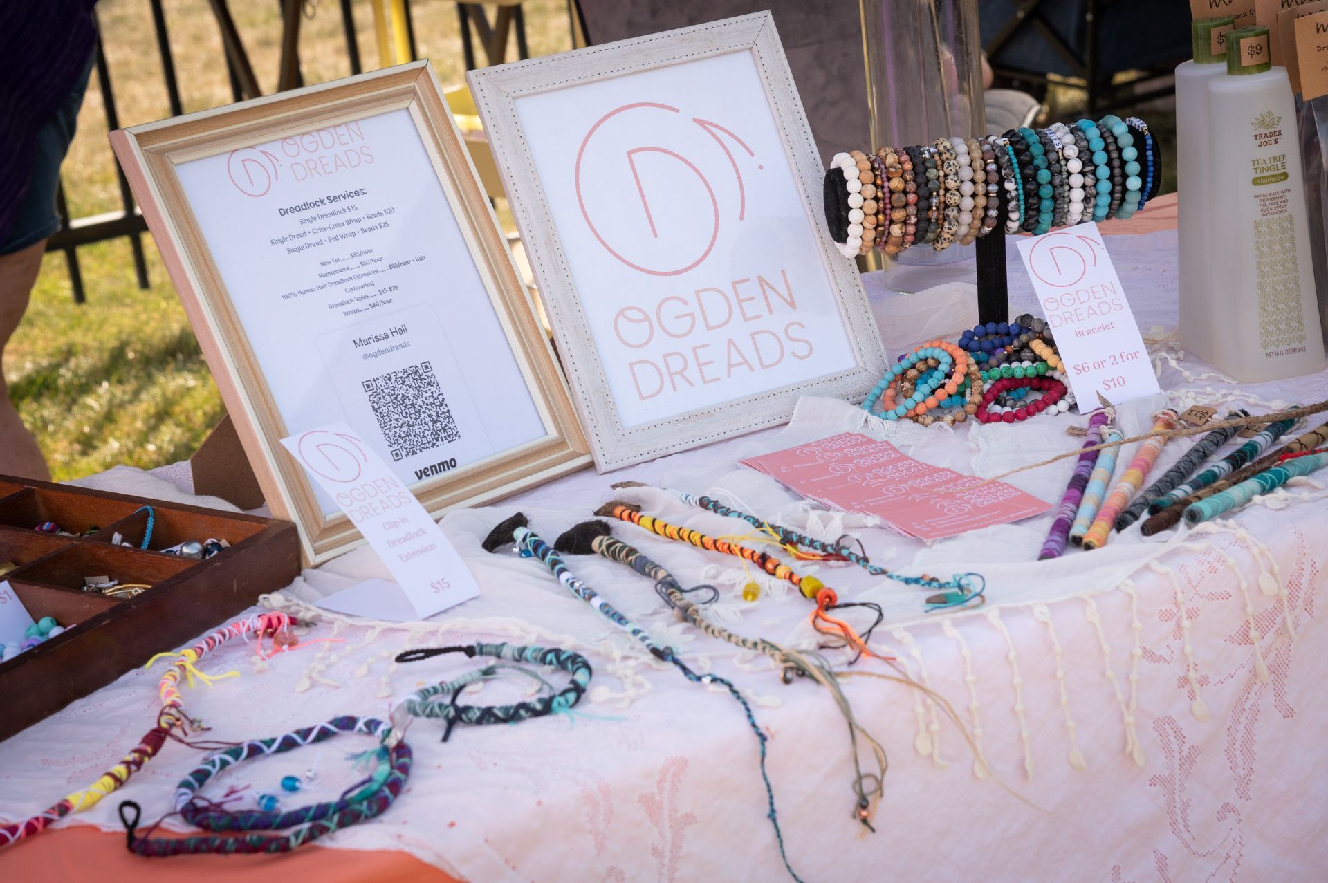 A table with bracelets and a sign that says ogden dreads on it.