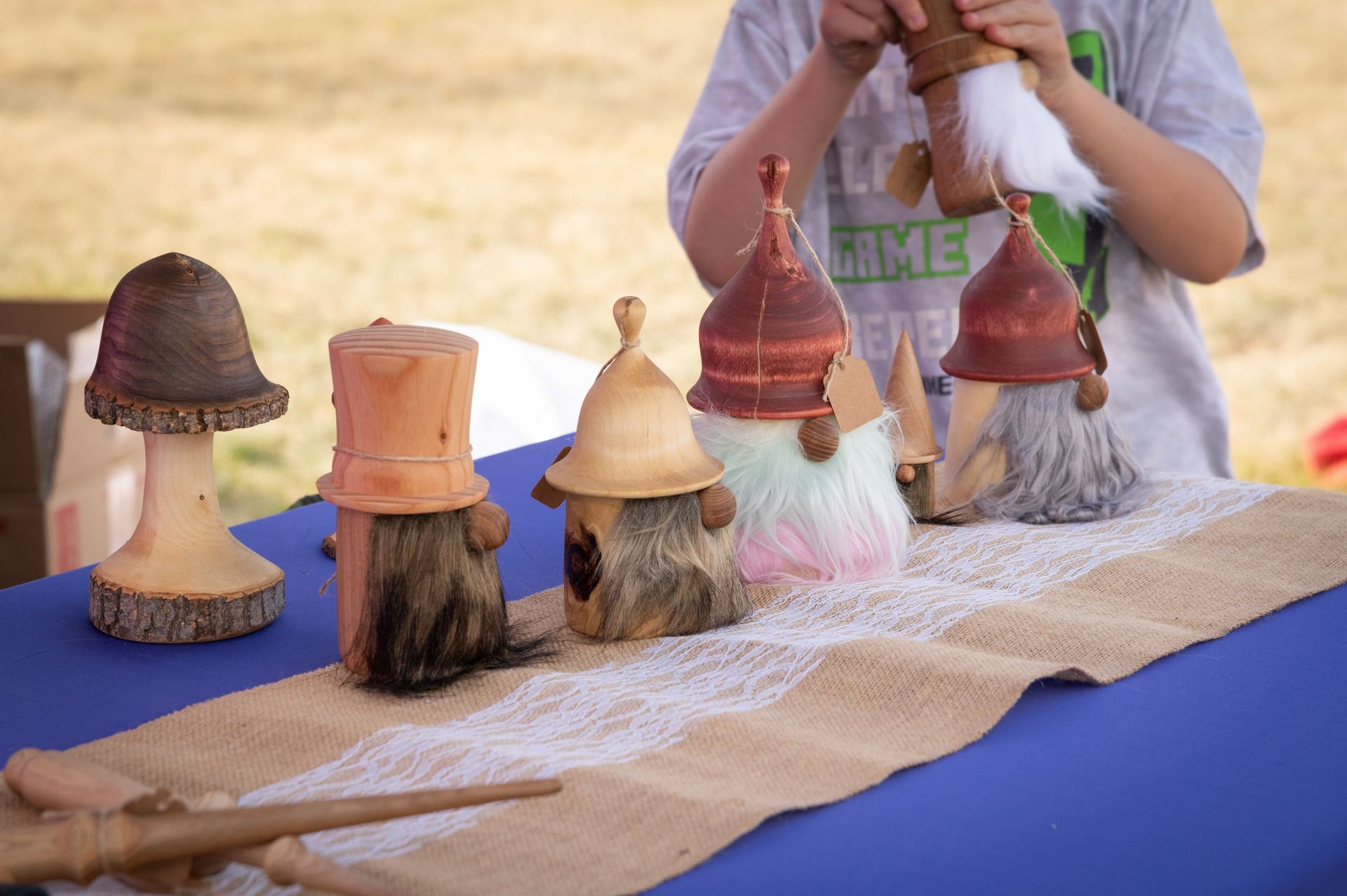 A boy is sitting at a table with a bunch of gnomes on it.