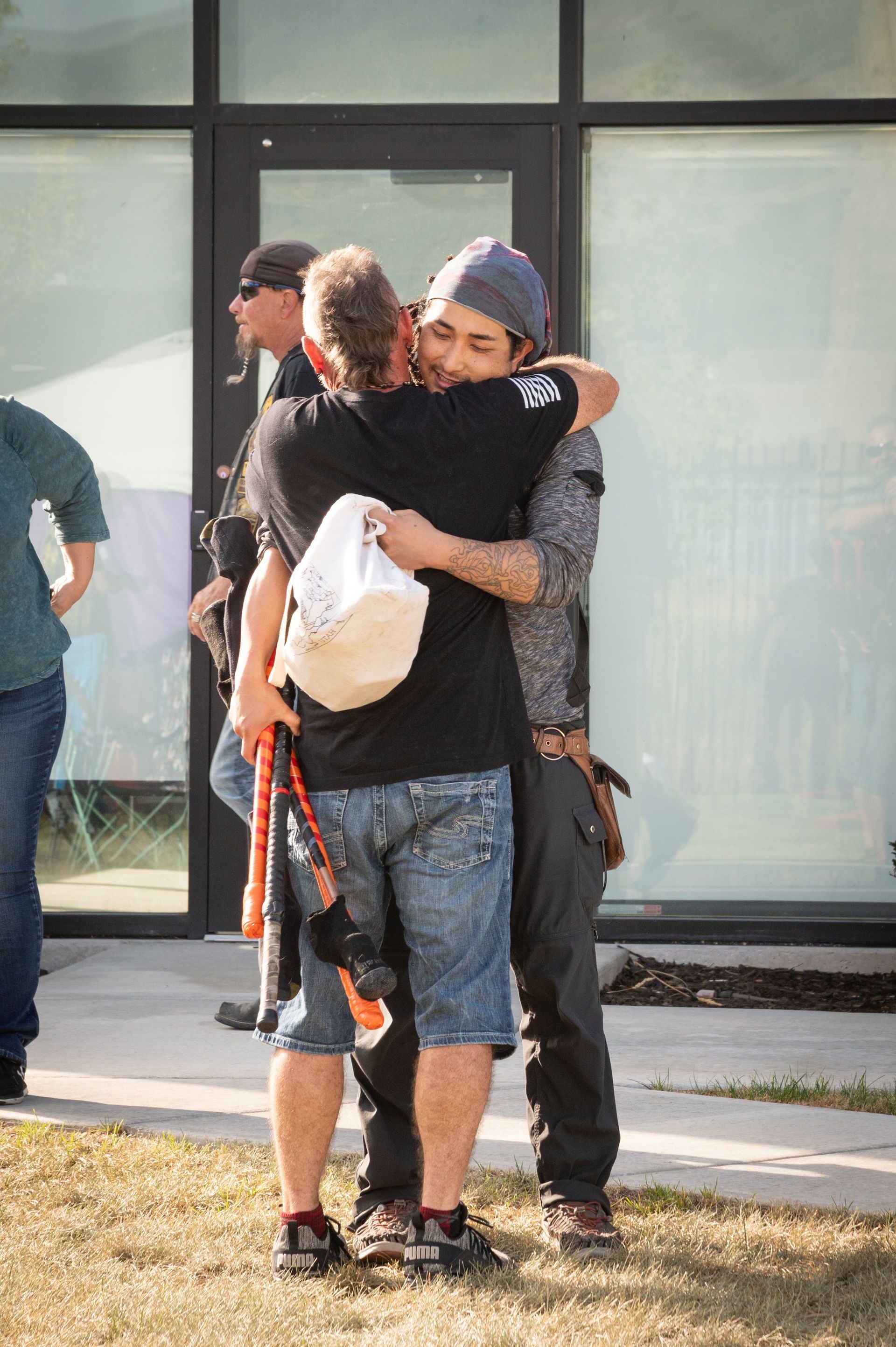 Two men are hugging each other in front of a building.