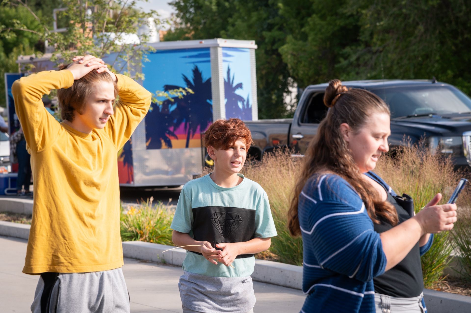 A woman is taking a picture of two children while a boy looks on.