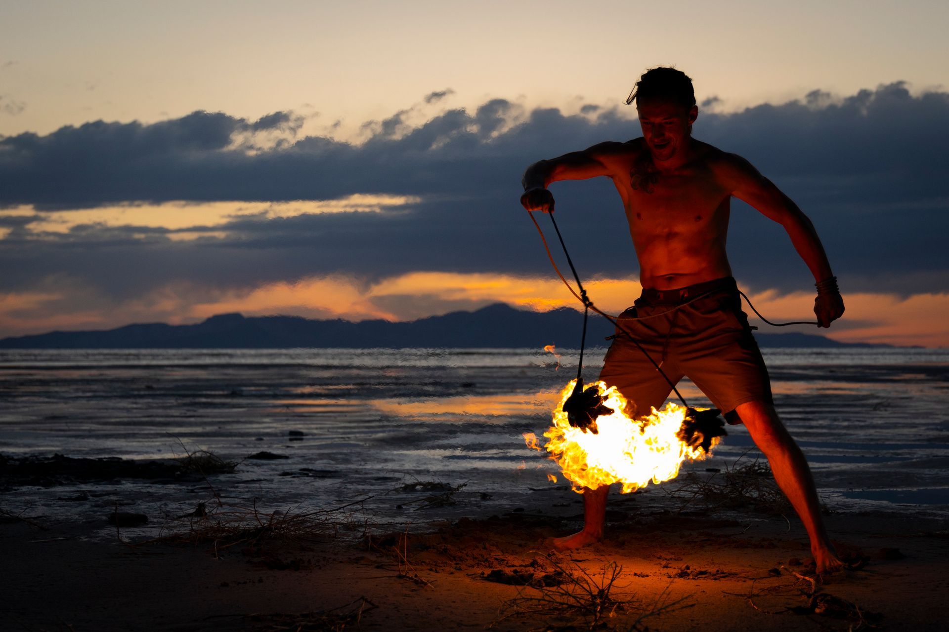 A man is holding a torch on the beach at sunset