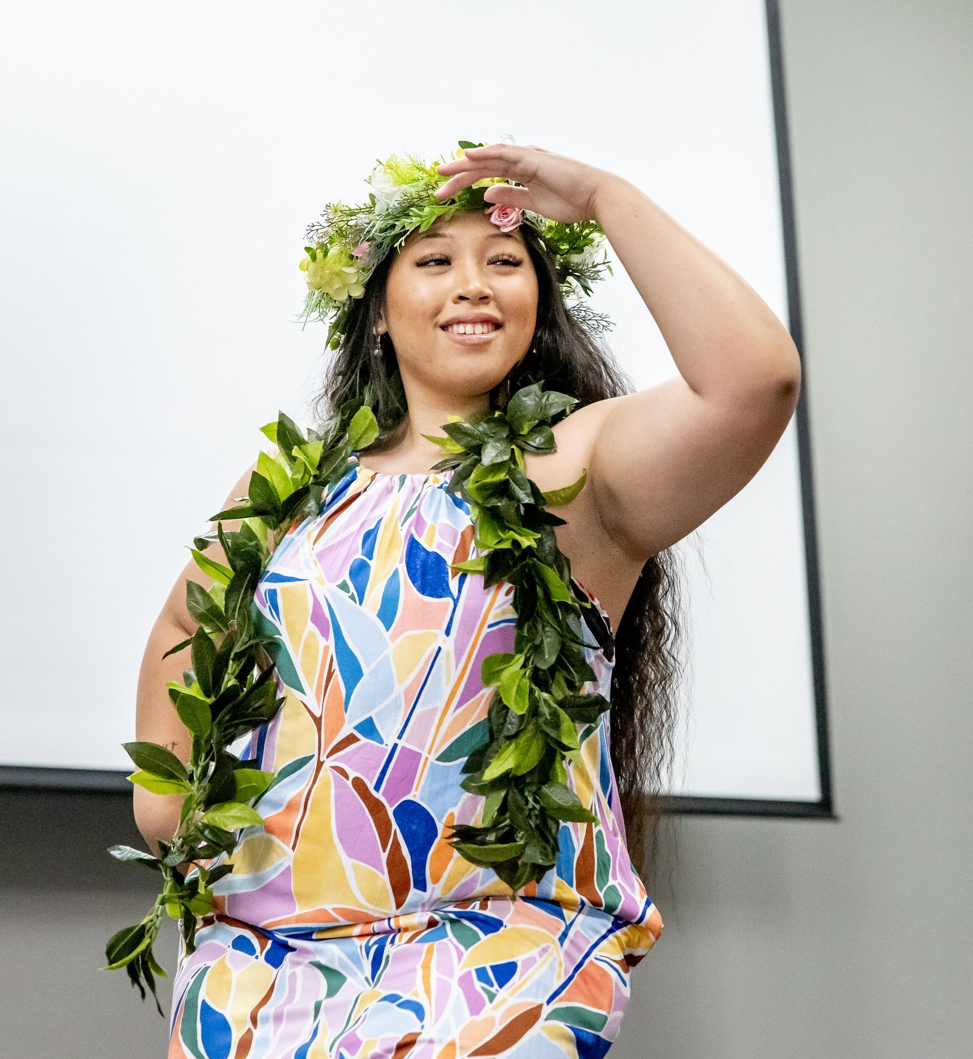 A woman in a colorful dress is wearing a lei around her neck.