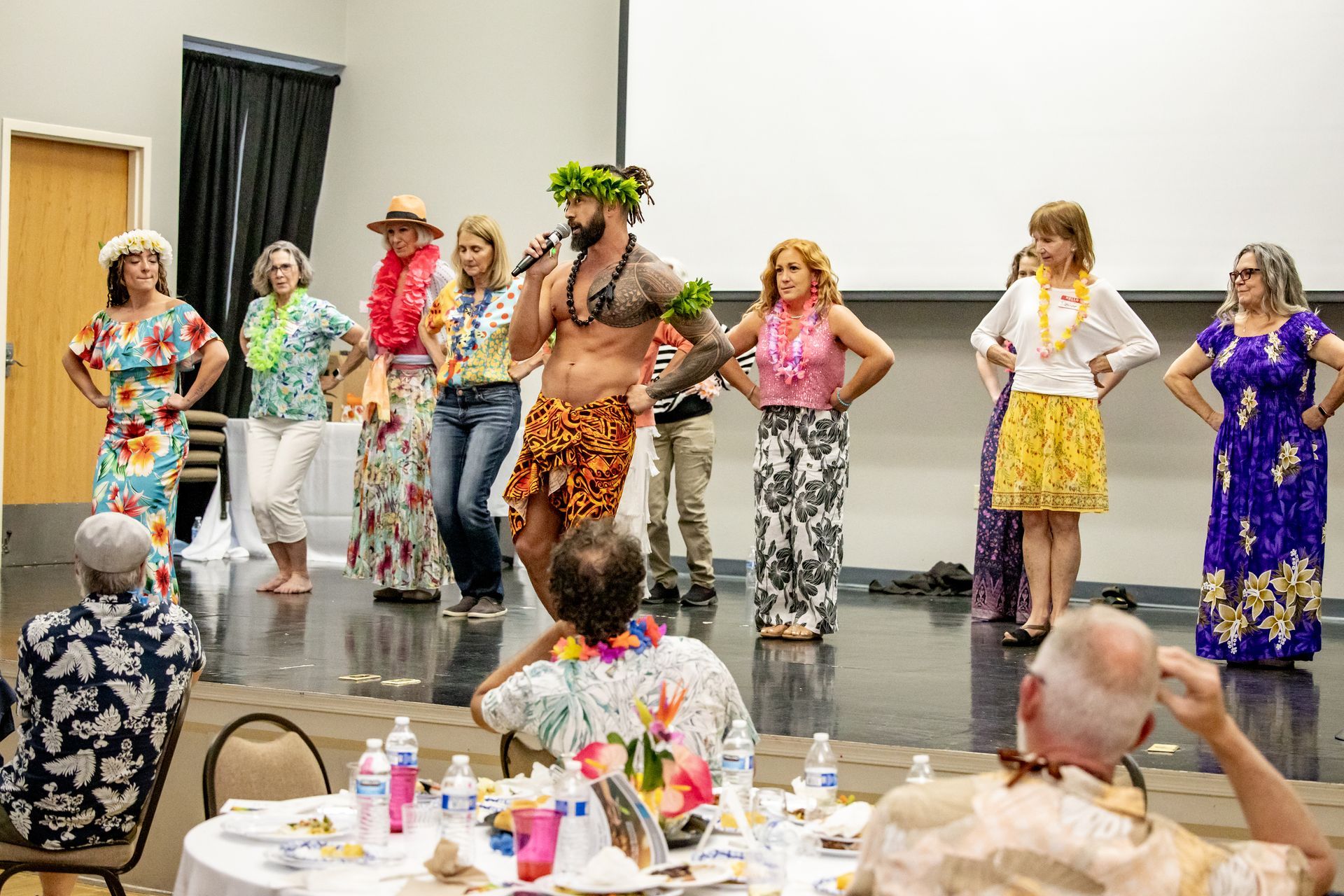 A group of people are dancing in a room while a man sings into a microphone.