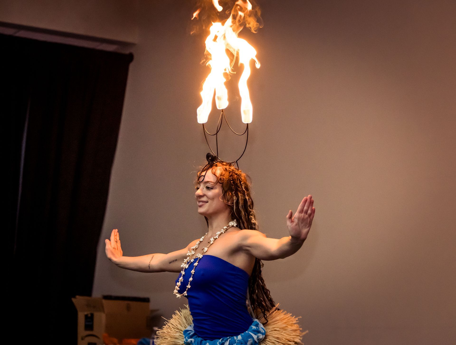 A woman in a blue dress is dancing with flames coming out of her head