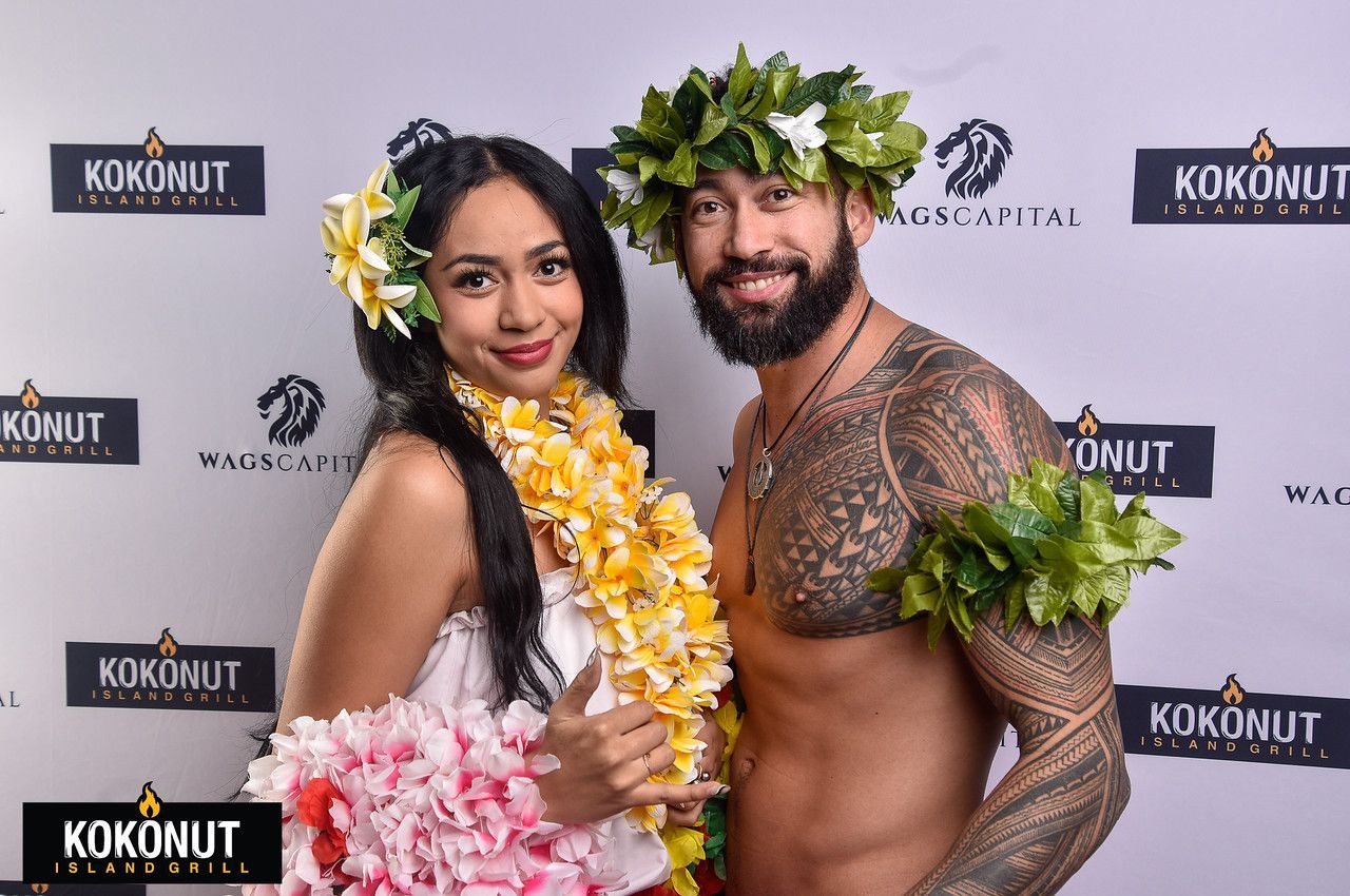 A man and a woman are posing for a picture while wearing lei.