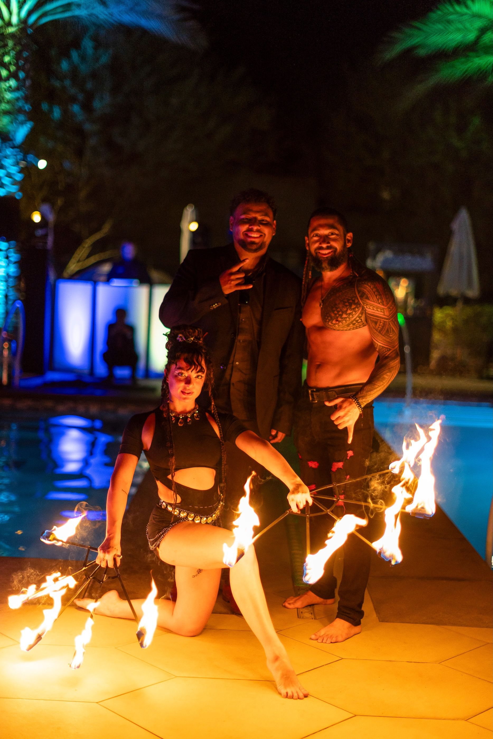 A group of people are posing for a picture in front of a pool while holding fire sticks.
