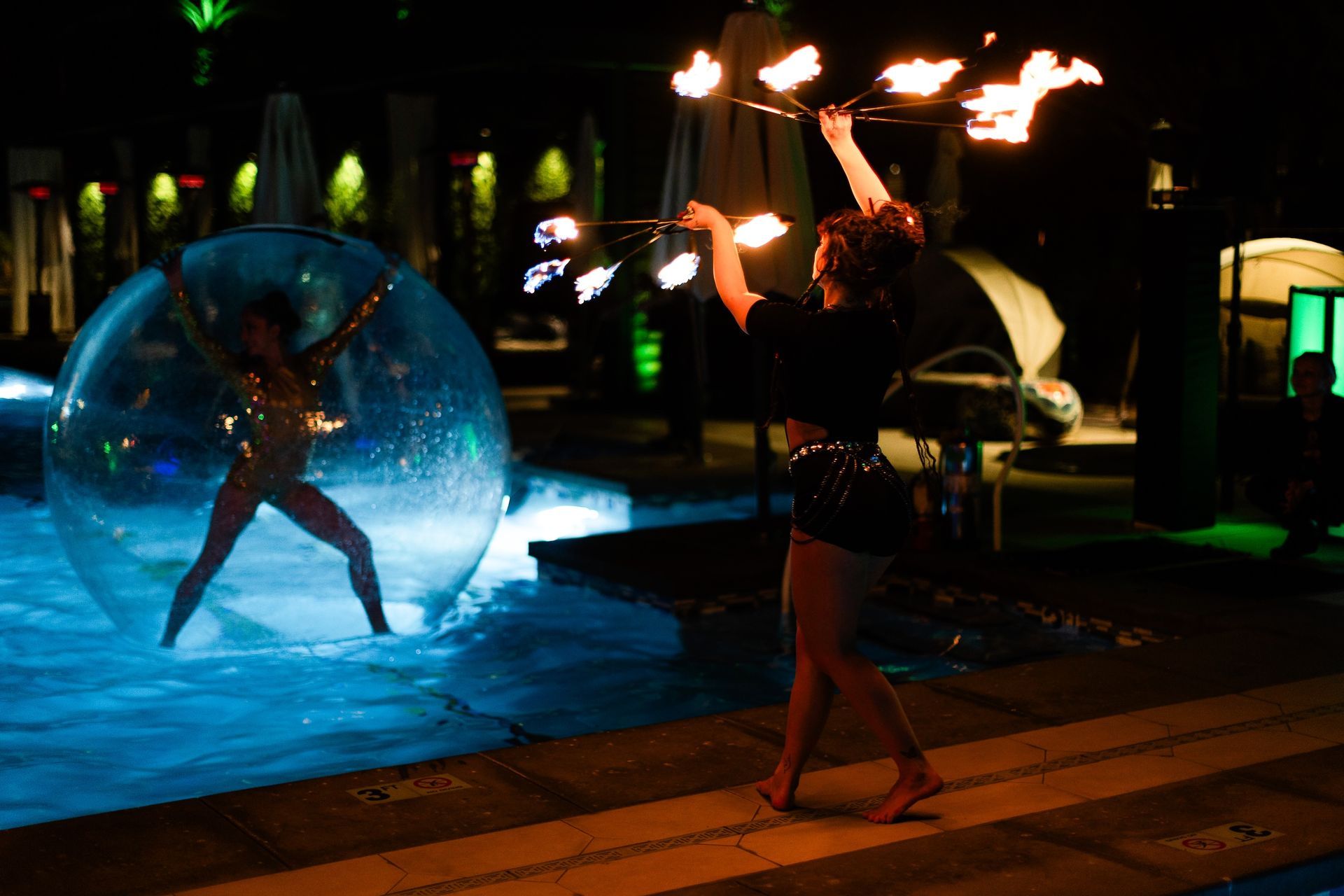 A woman is playing with fire in a pool at night.