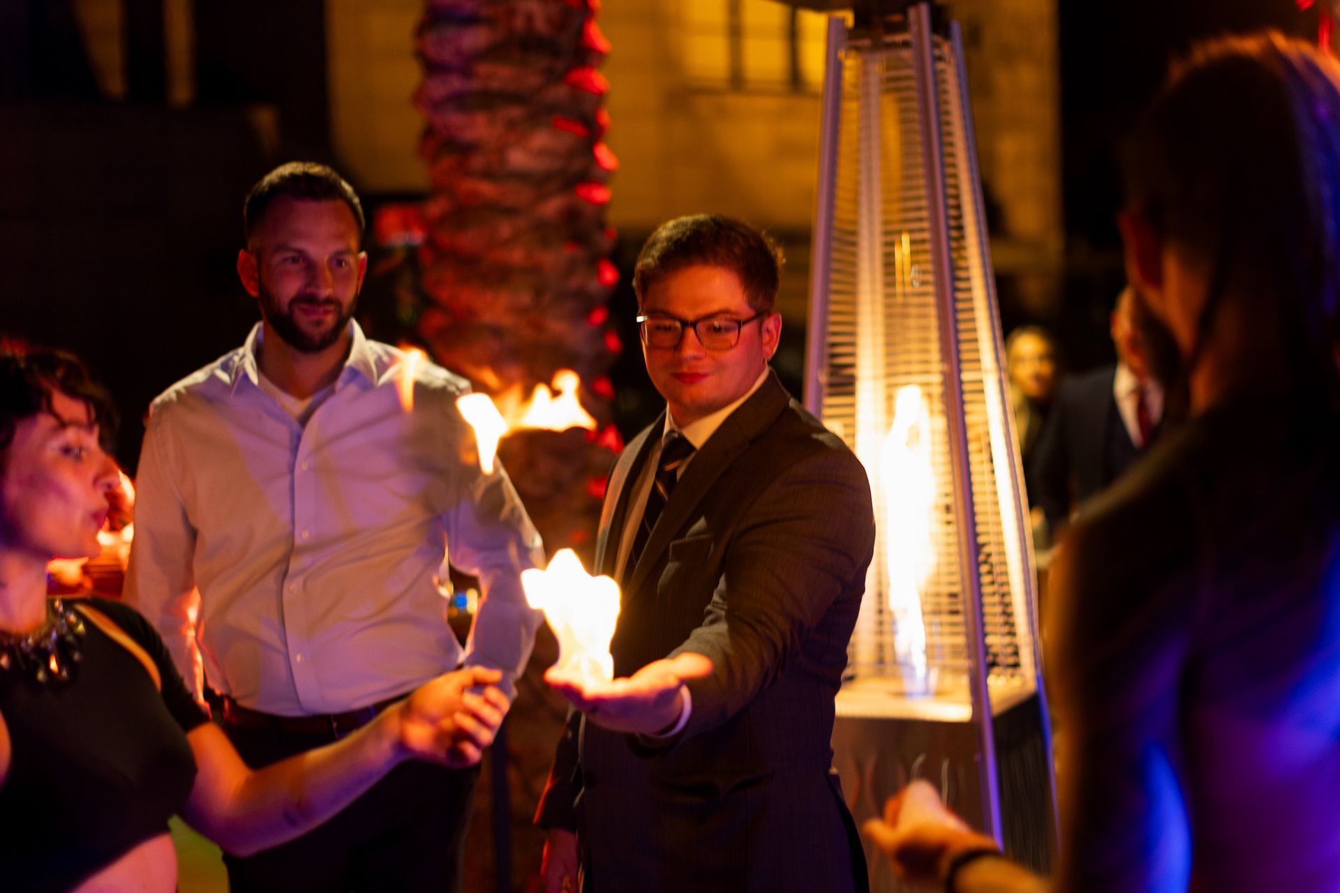 A man in a suit is holding a torch in his hand in front of a group of people.