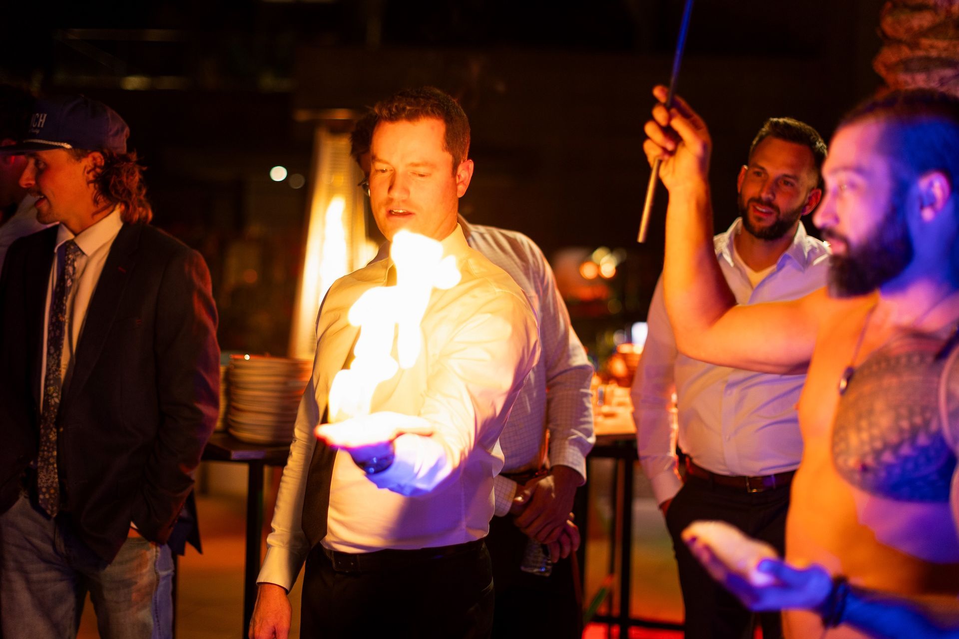 A group of men are standing around a man holding a fireball in his hand.