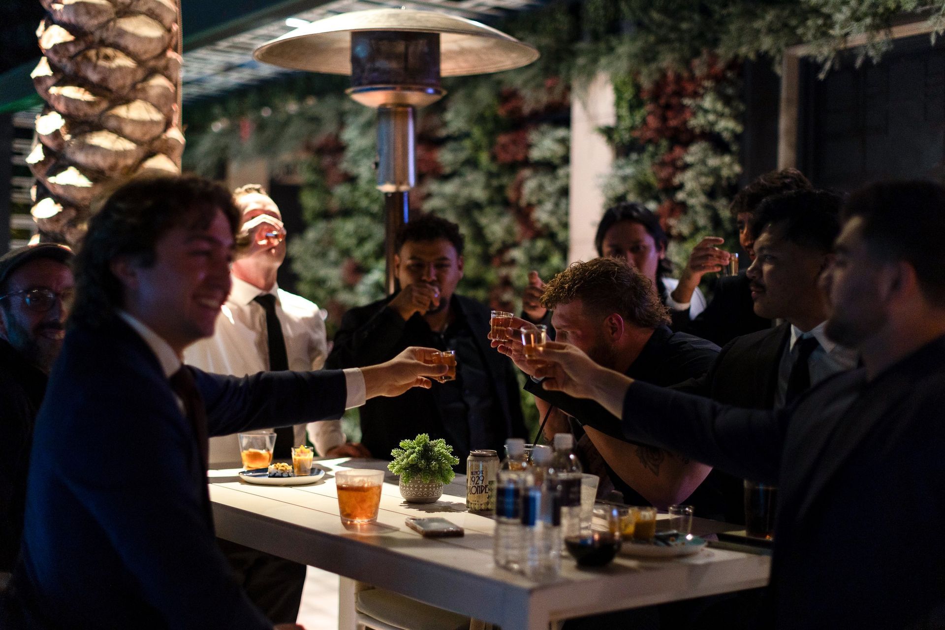 A group of men are sitting at a table toasting with beer.