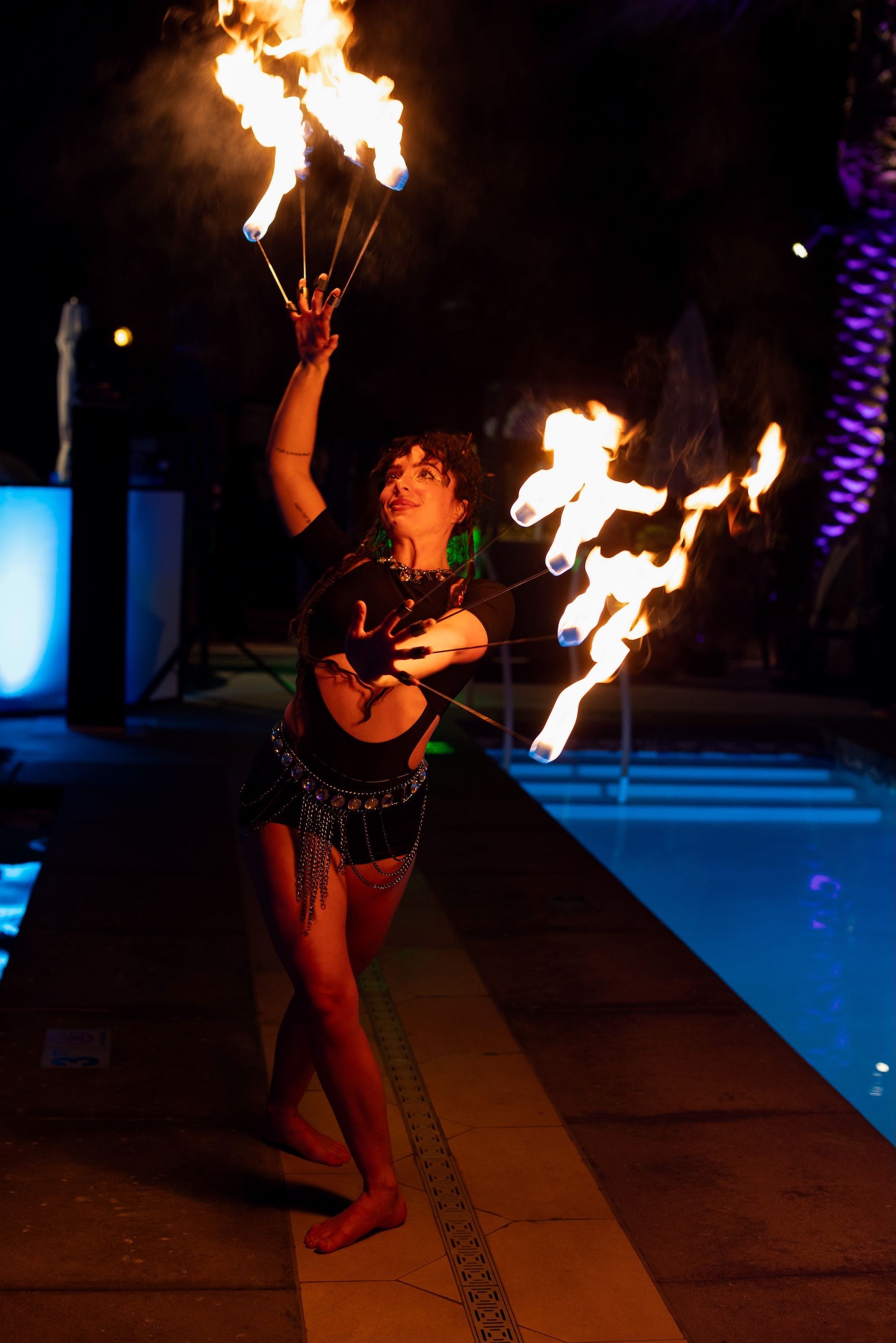 A woman is holding a bunch of flames in her hands in front of a pool.